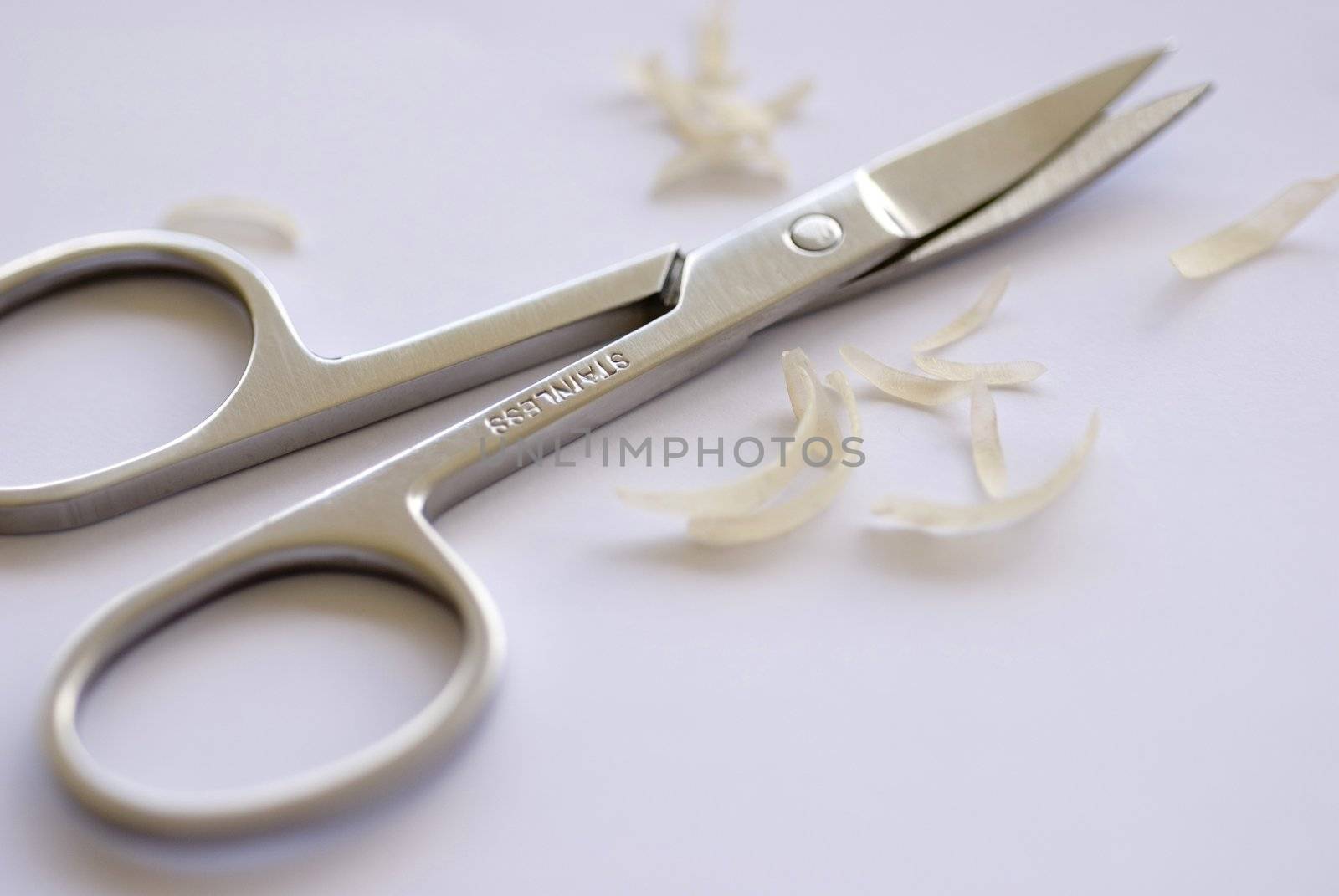 a pair of curved nail scissors and some nail clippings