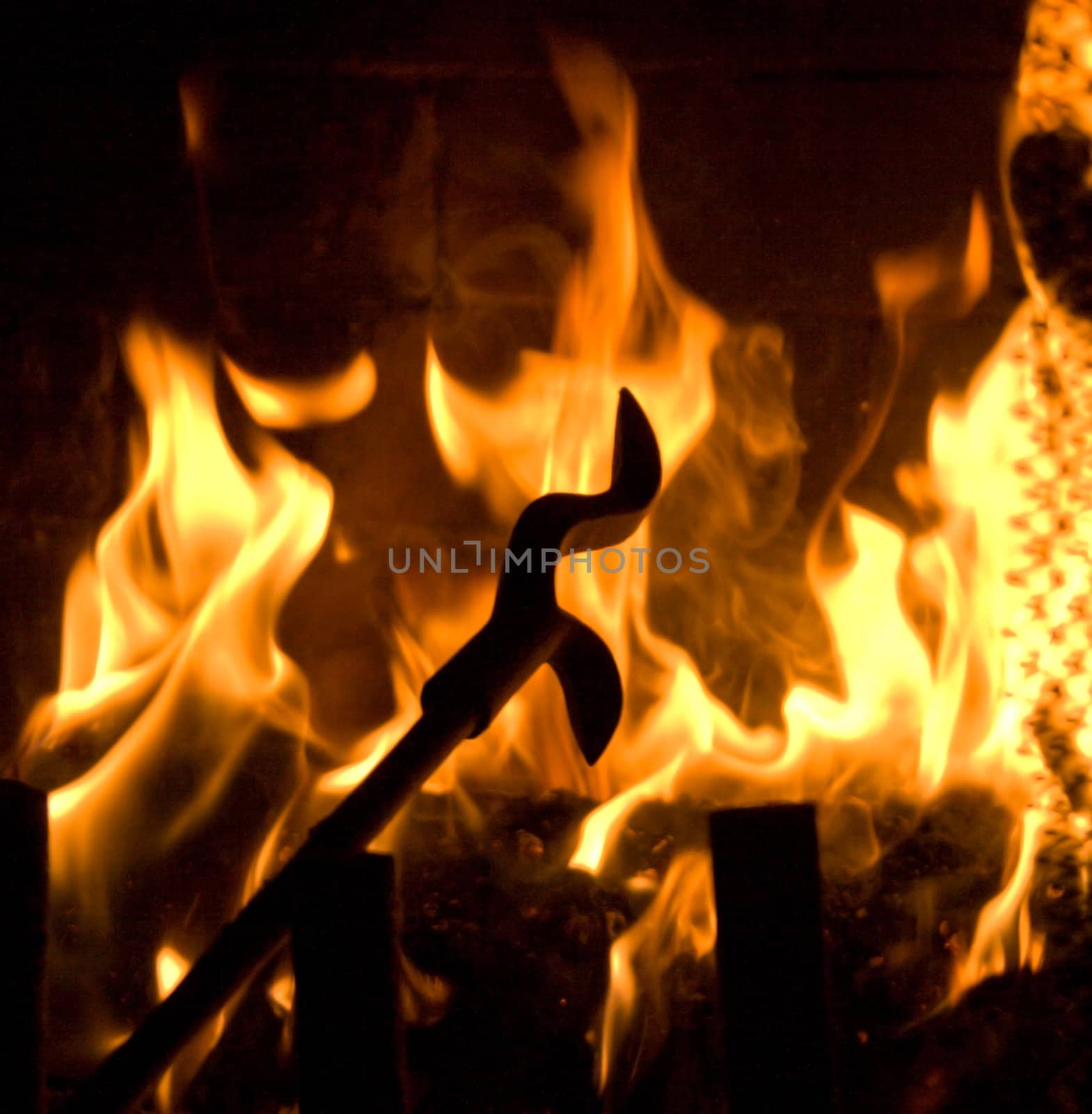 Fireplace Poker Silhouette in Flames of Fire Background.