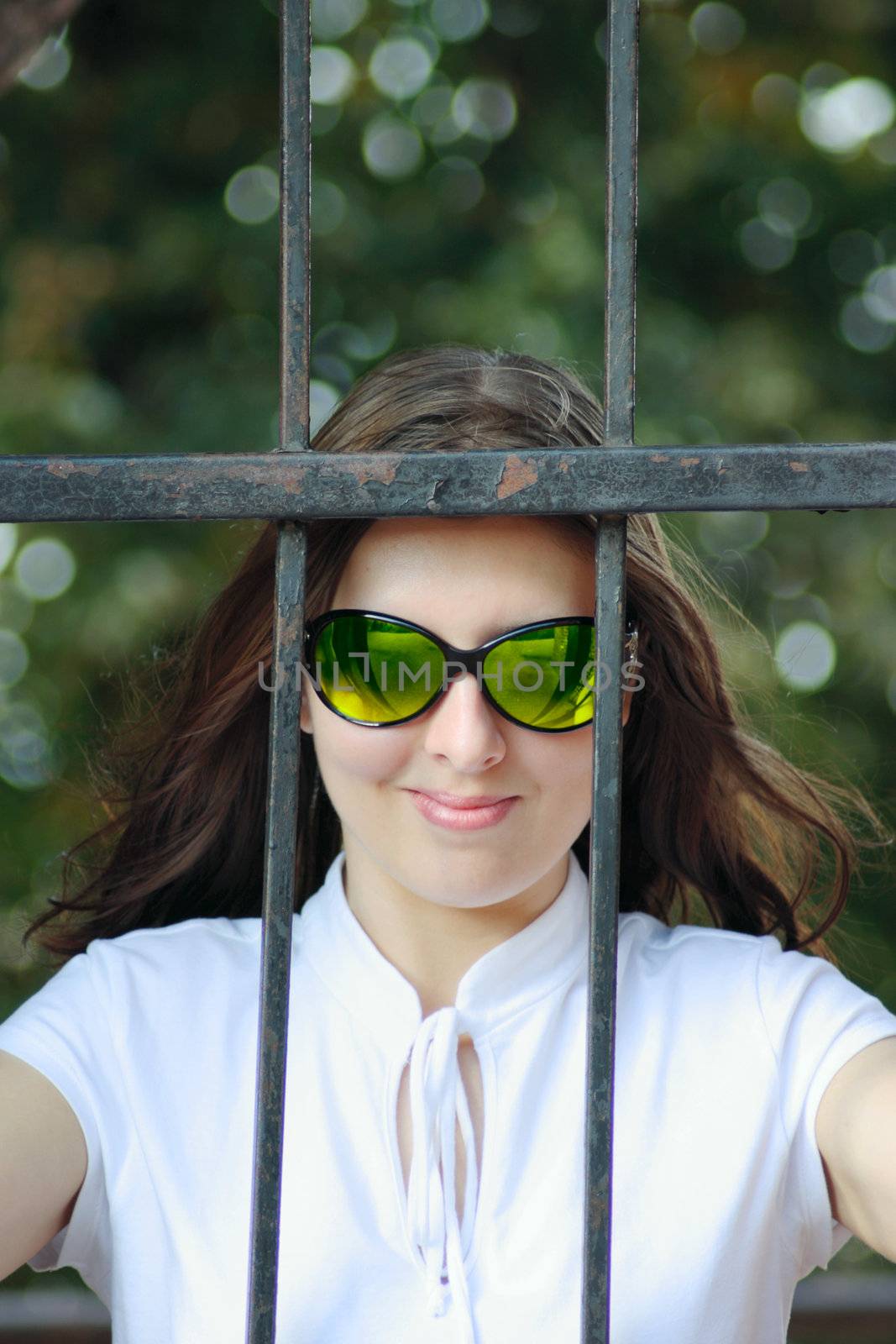 Portrait of the young woman in sun glasses behind an iron protection