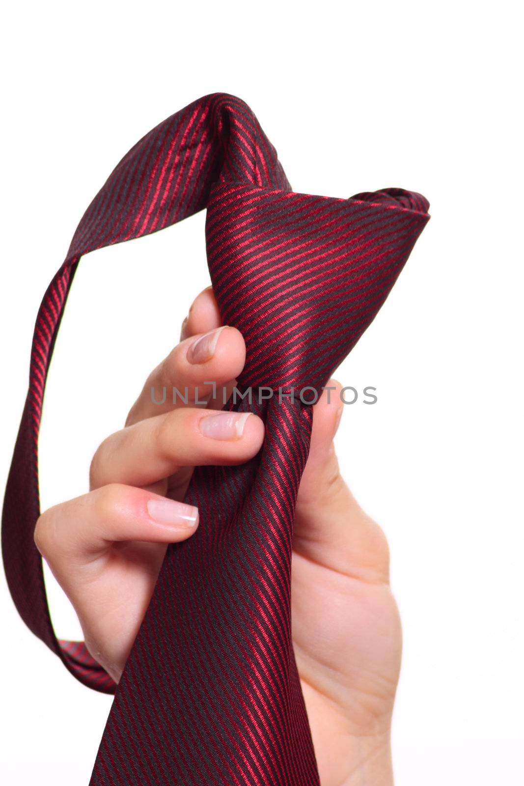 Female hand holding a red striped tie with the fastened knot removed close up