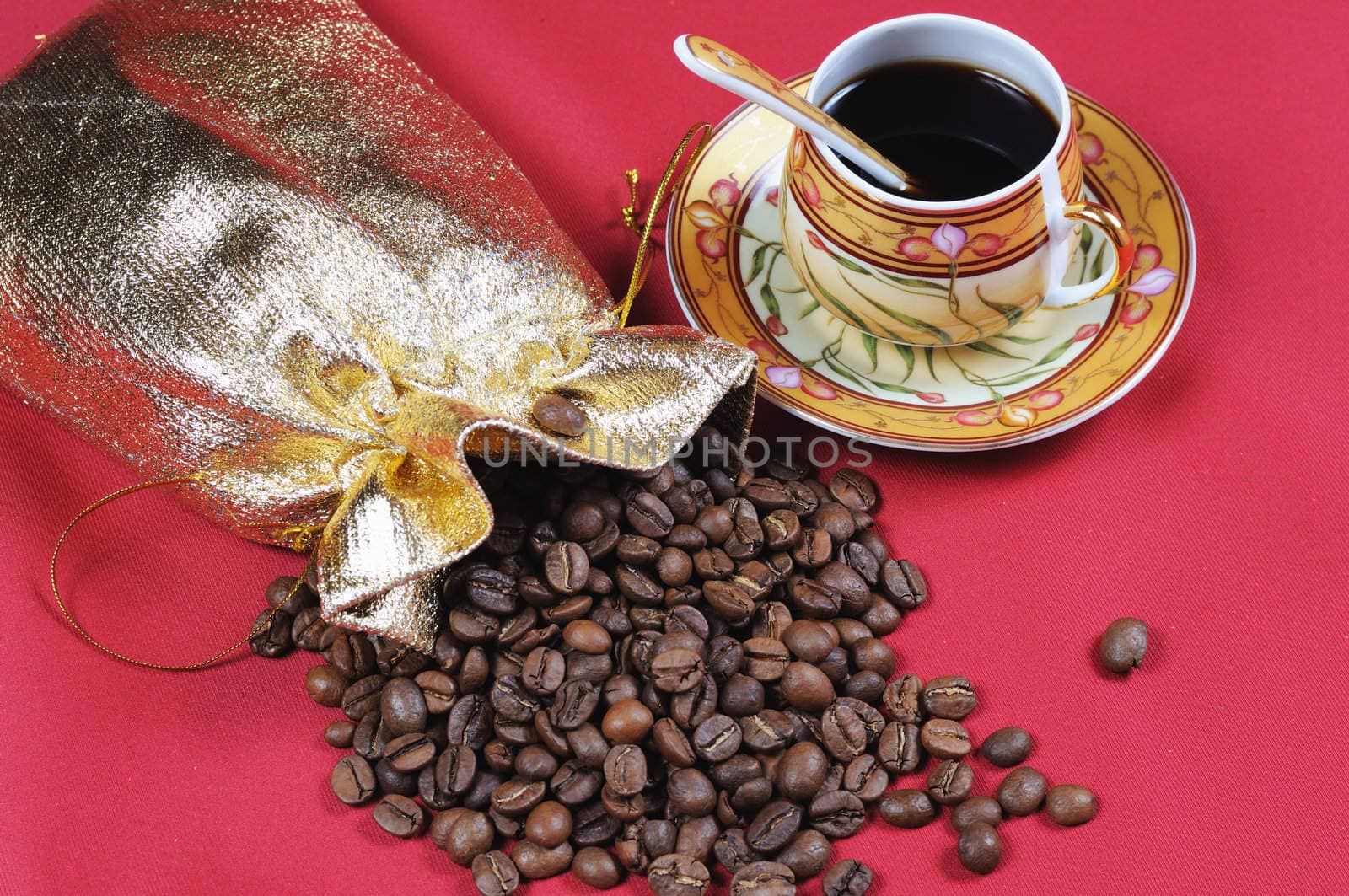 Heap of coffee bean and the cup on a red background