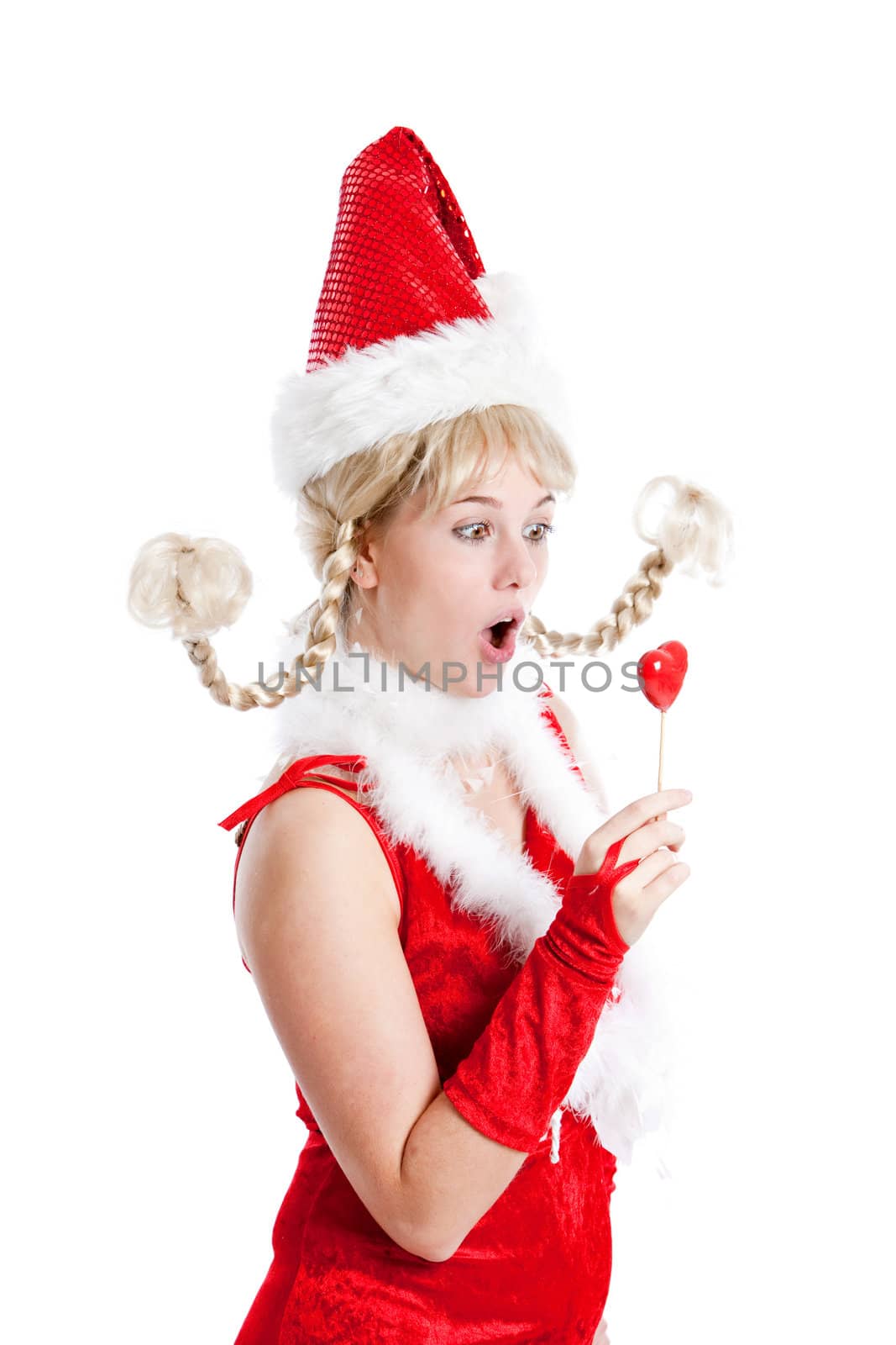 Cute young girl in santa outfit looking shocked at her lollipop