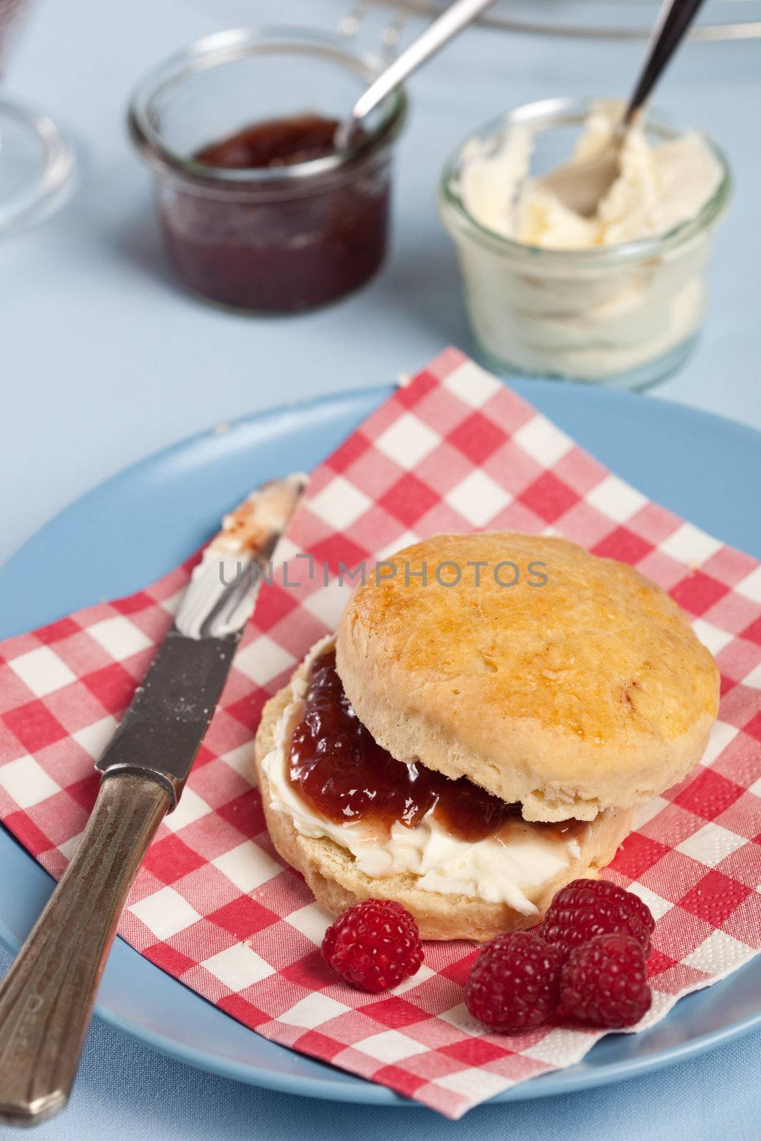 Freshly baked scone with raspberry jam and clotted cream