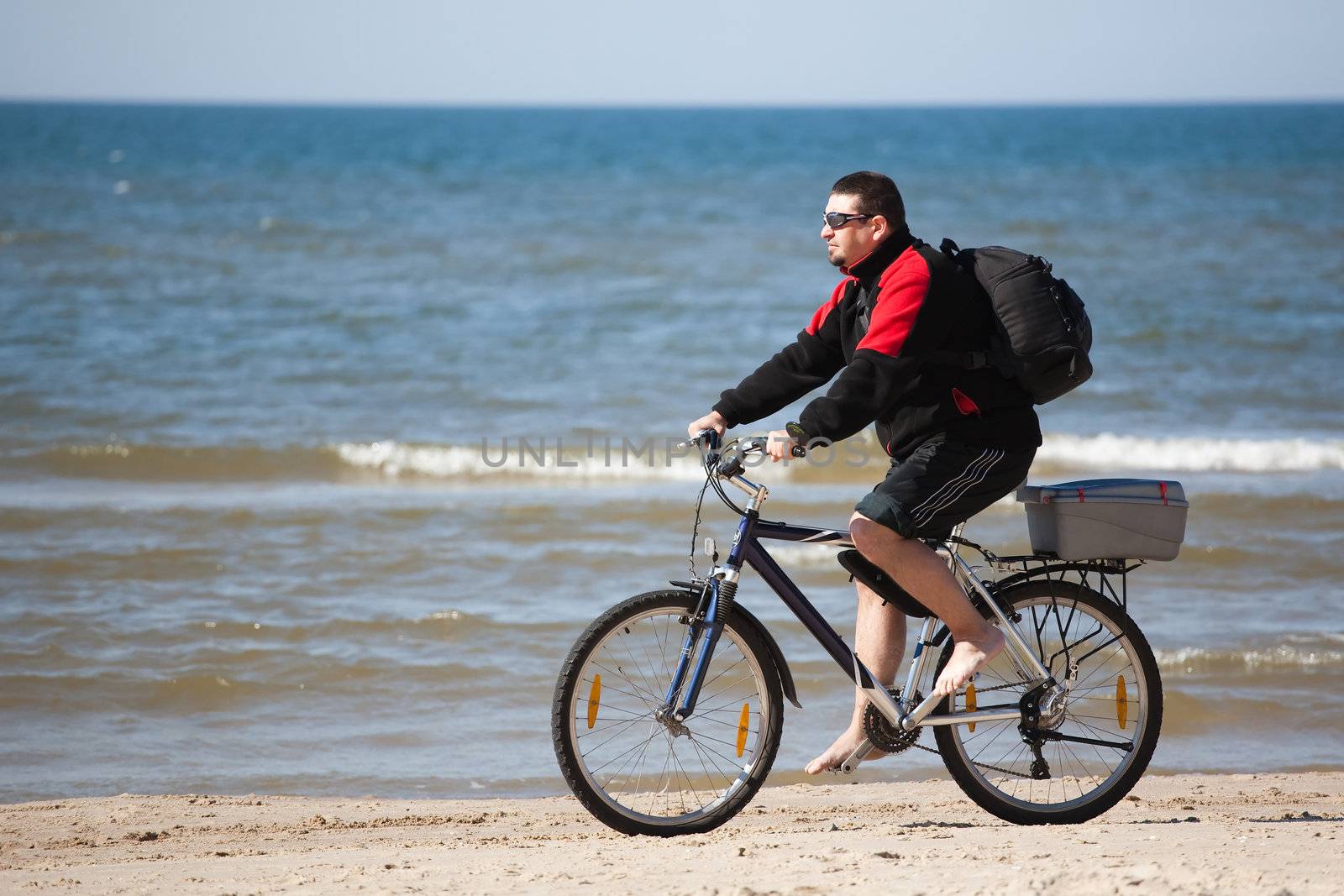 man riding mountain bike on the beach by furzyk73