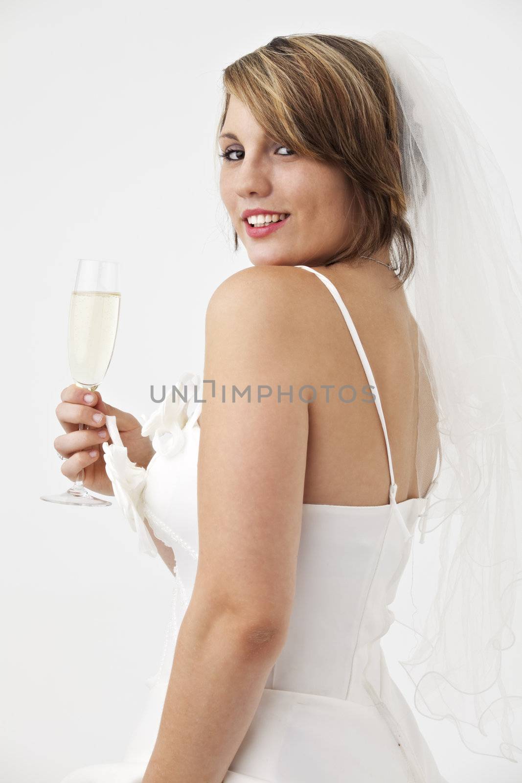 beautiful young bride in a wedding dress with a veil holding a glass of champagne