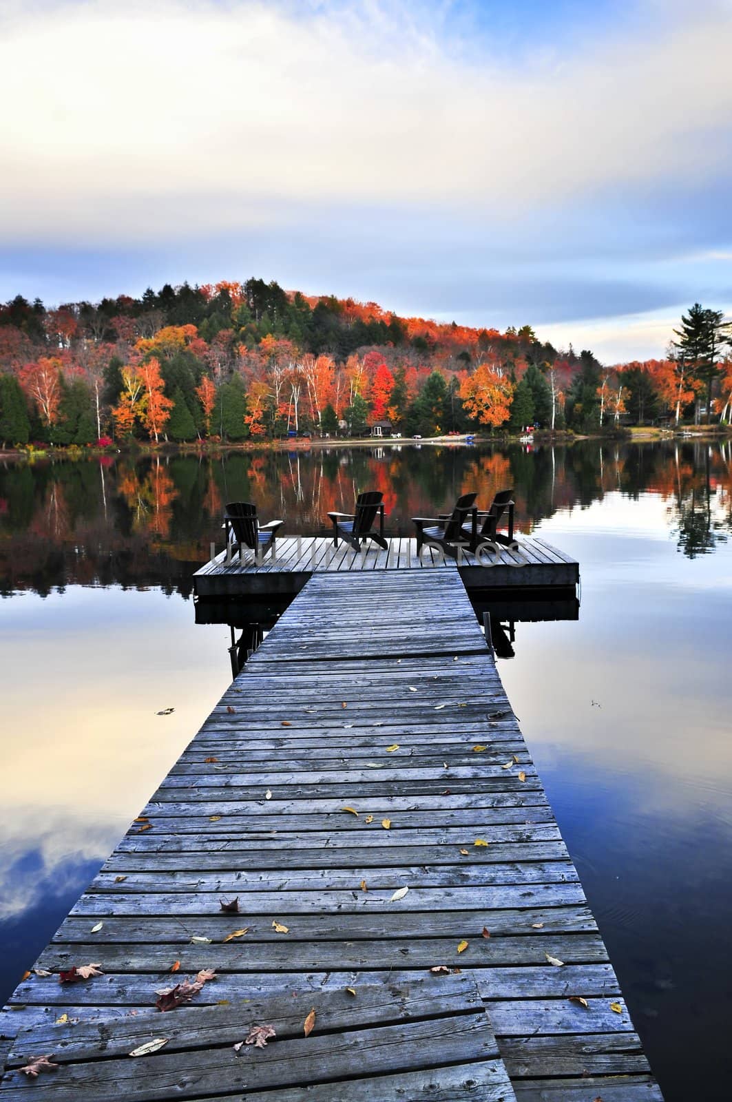 Wooden dock with chairs on calm fall lake