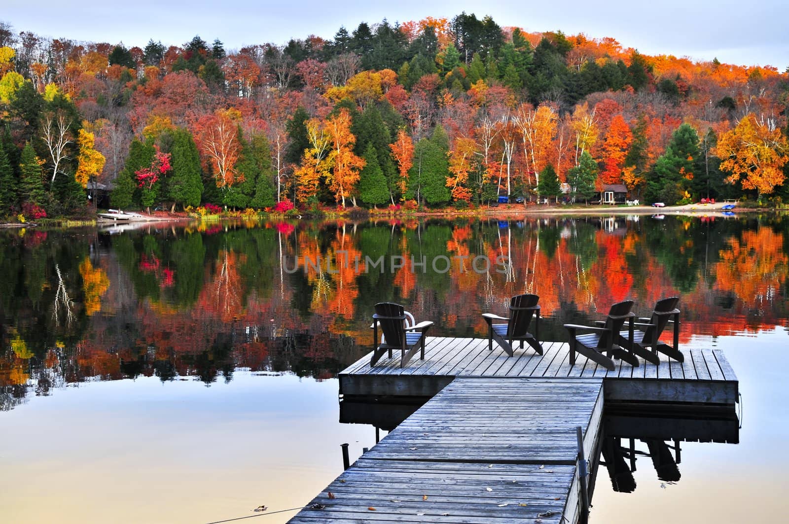 Wooden dock with chairs on calm fall lake