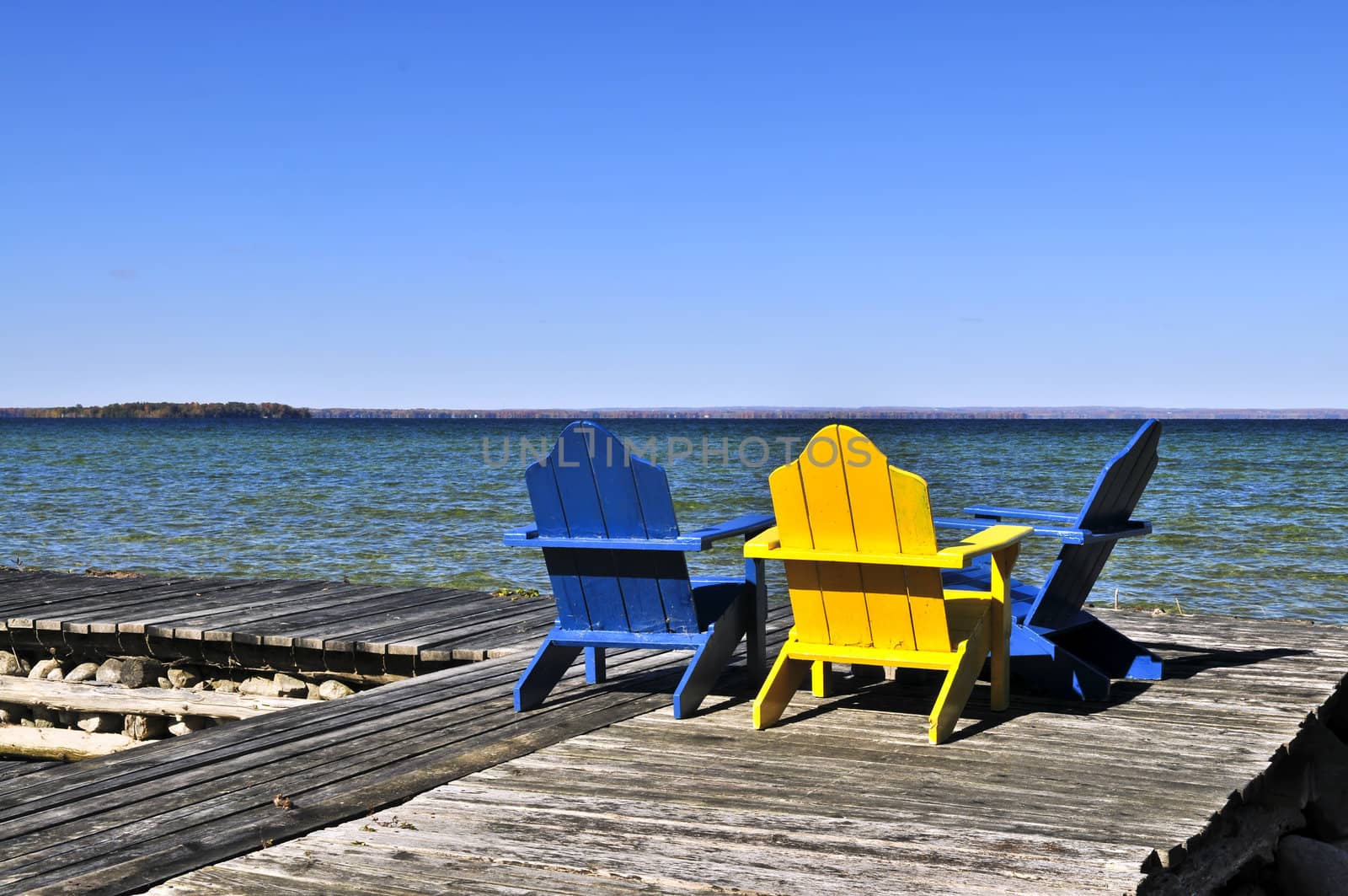 Painted wooden chairs on dock at a lake