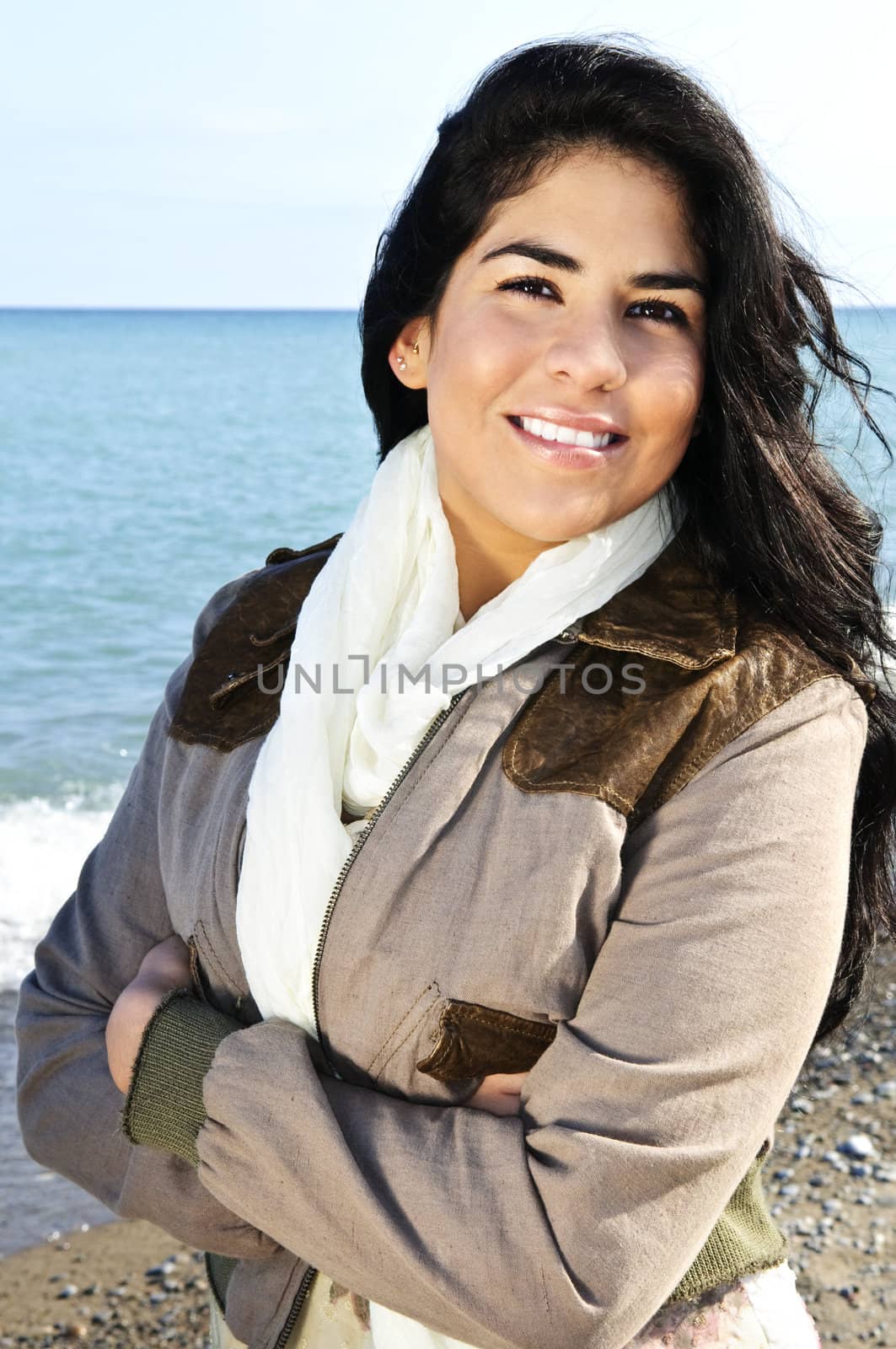 Portrait of beautiful smiling brunette girl at cool windy beach