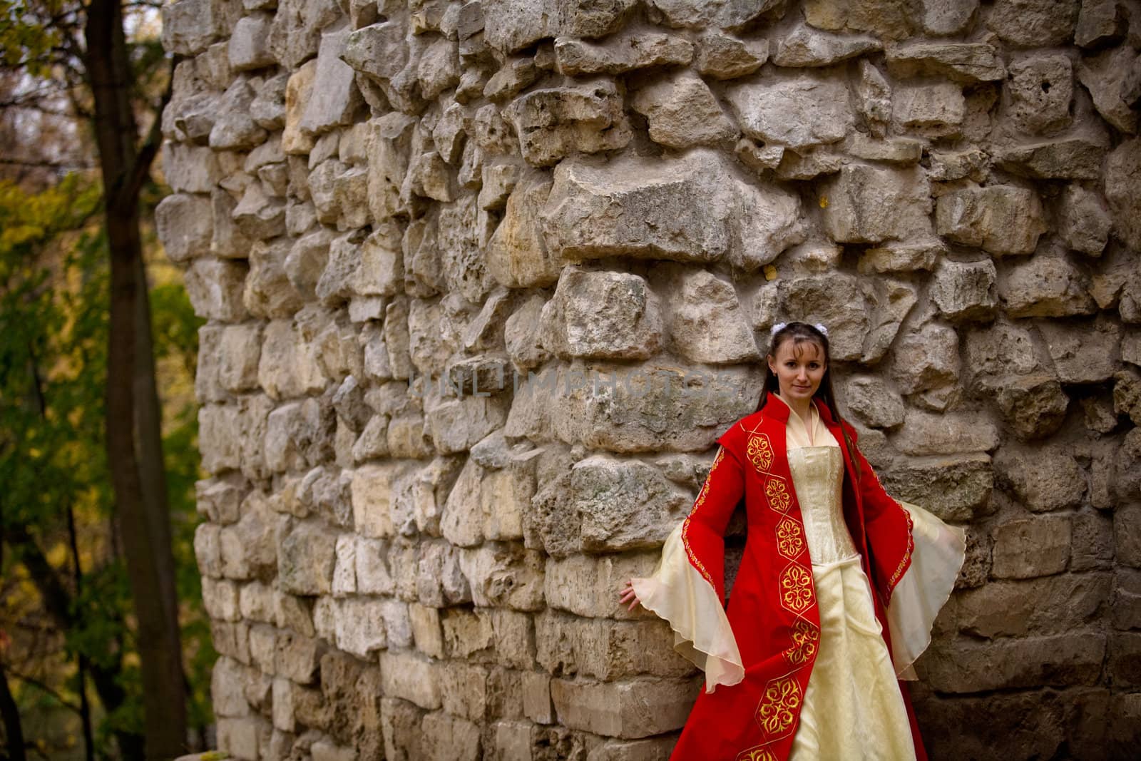 lady in medieval red dress standing near old wall
