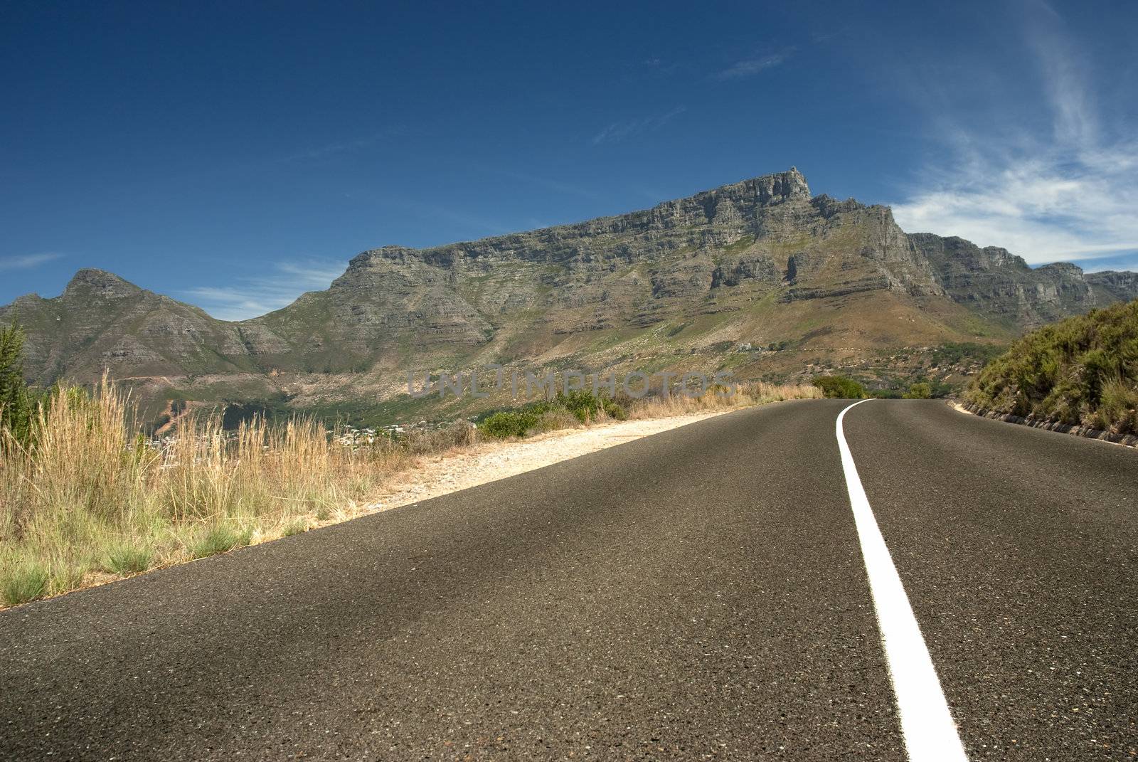 Road leading toward Table mountain in the background with blue sky and clouds