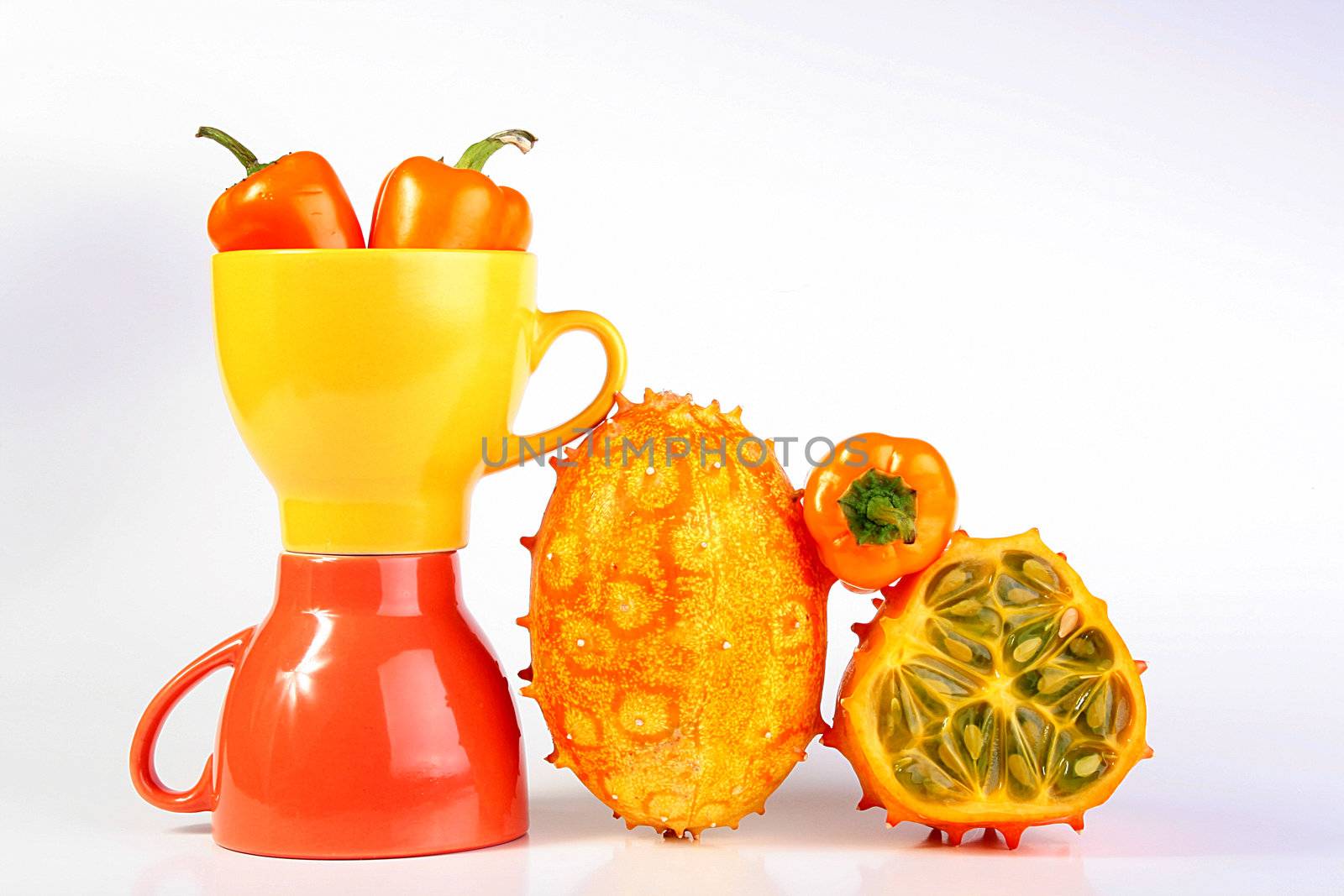 Two cups with vegetables a hot pepper and Kiwanos, one of Kiwanos is cut. Exotic fruit Kiwanos, is used for preparation of salads and for an ornament of dishes.