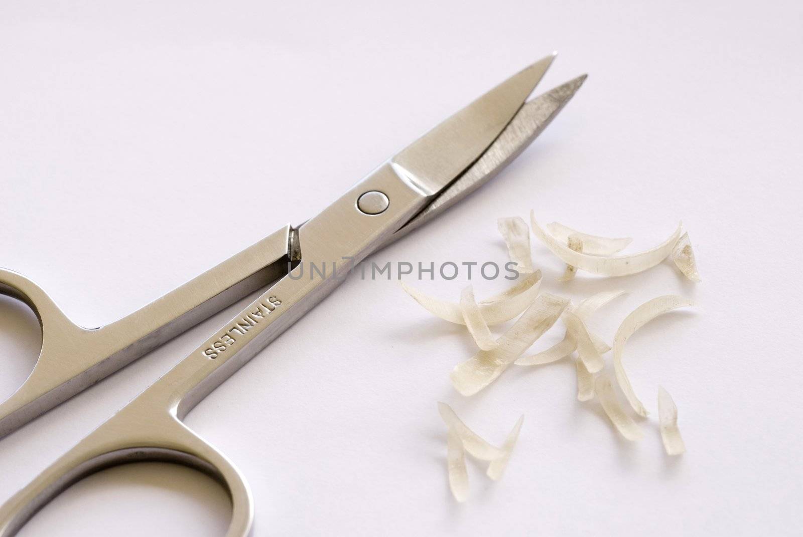 a pair of curved nail scissors and some nail clippings