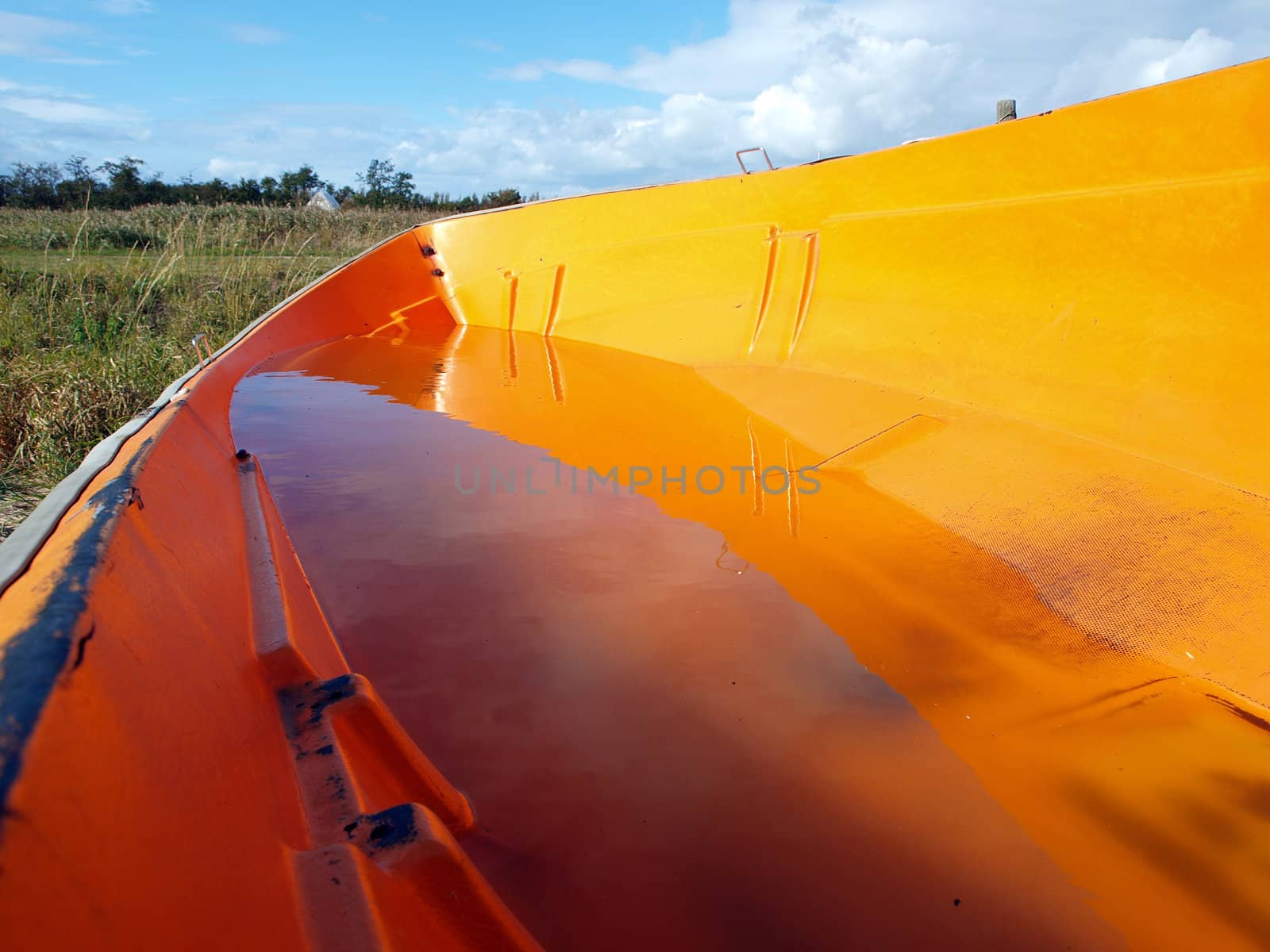 Small orange fishing skiff boat full of rain water