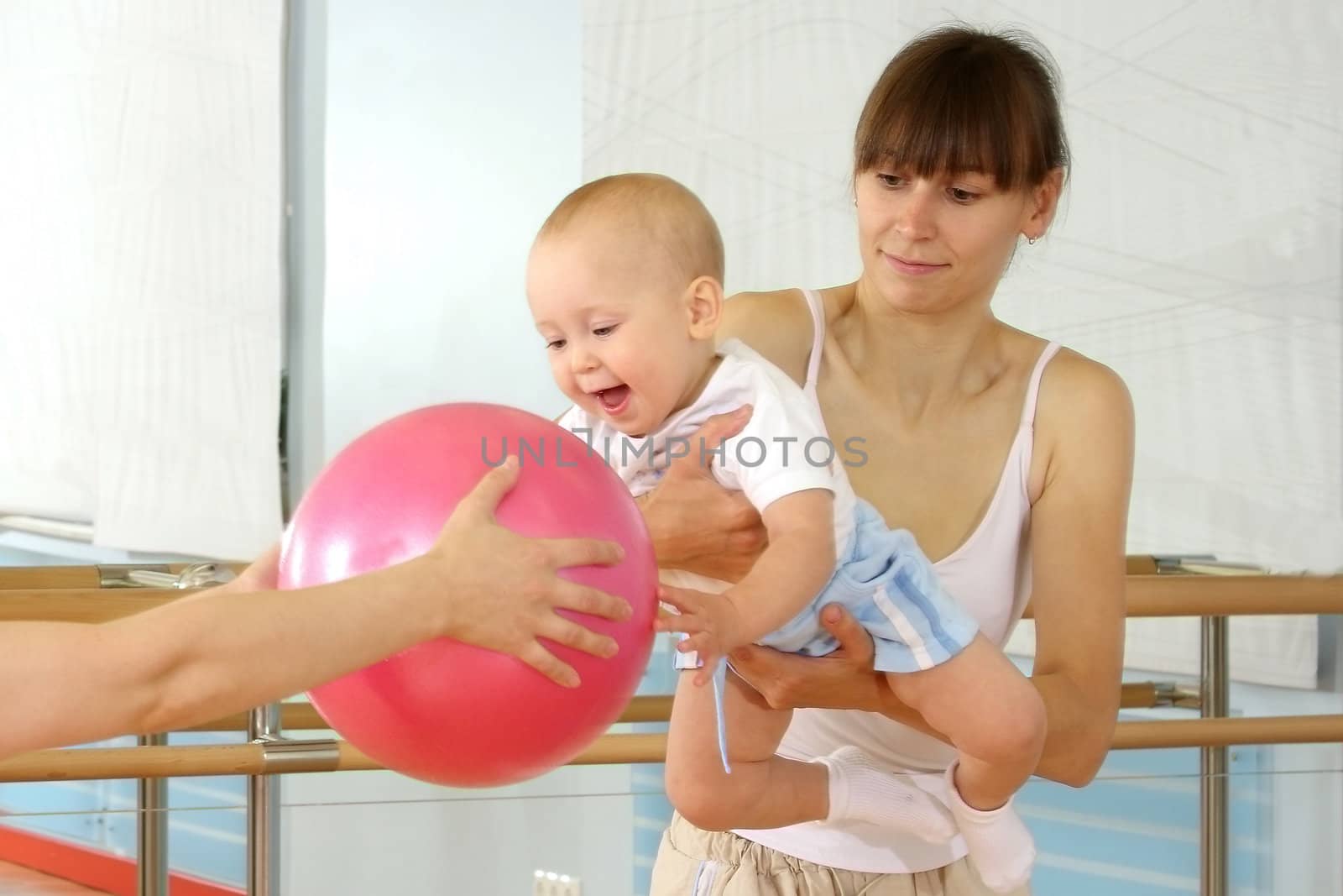 Mother and the child are engaged with the instructor in a sports hall
