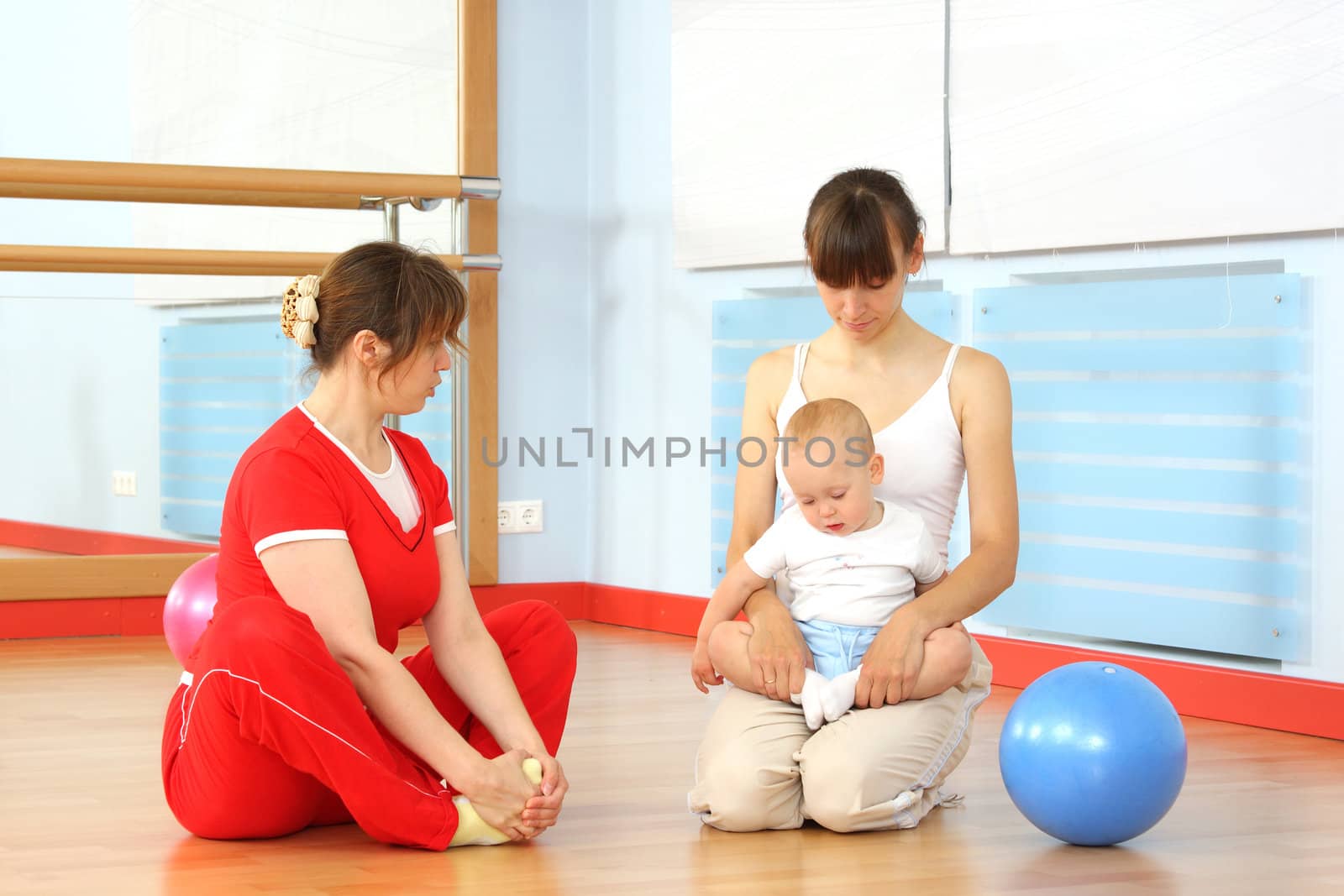 Mother and the child are engaged with the instructor in a sports hall
