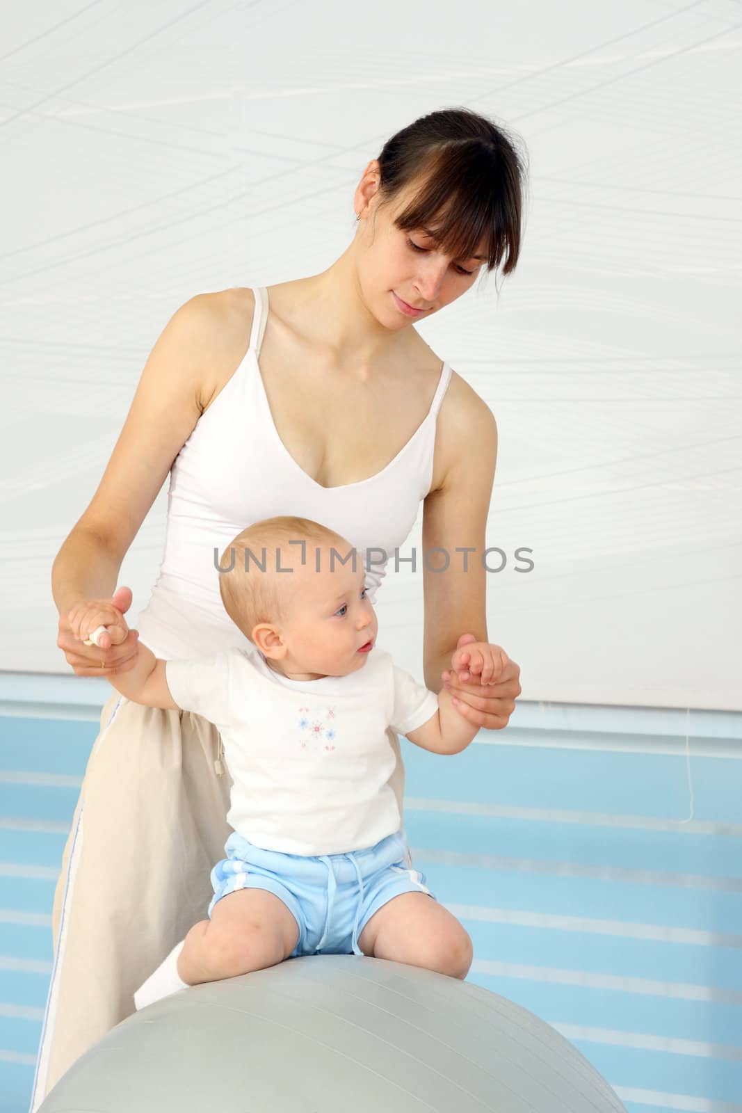 Mother and the child are engaged with the instructor in a sports hall
