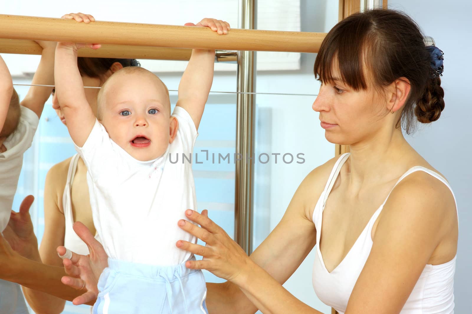 Mother and the child are engaged with the instructor in a sports hall
