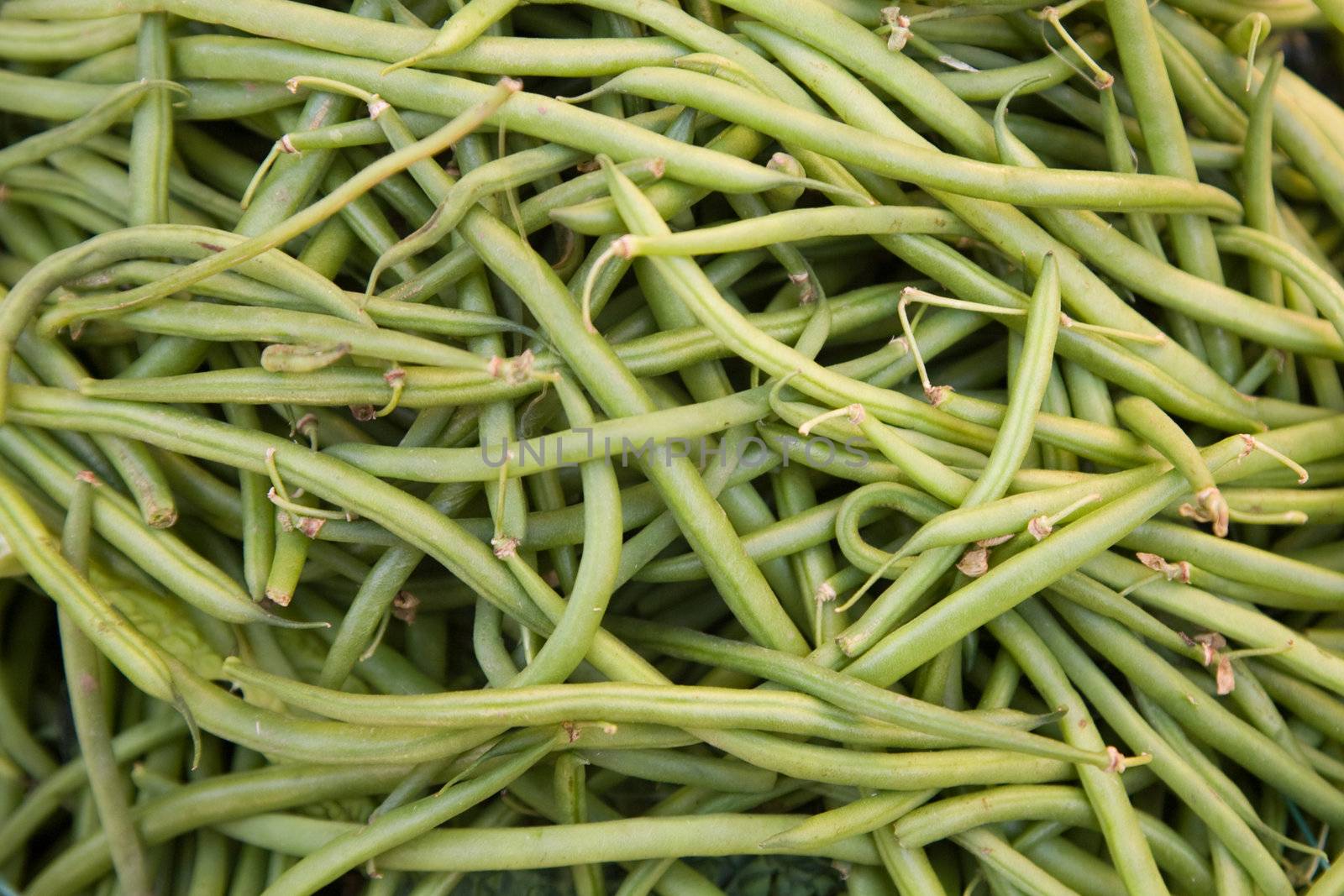 Group of fresh green beans on produce market stall.