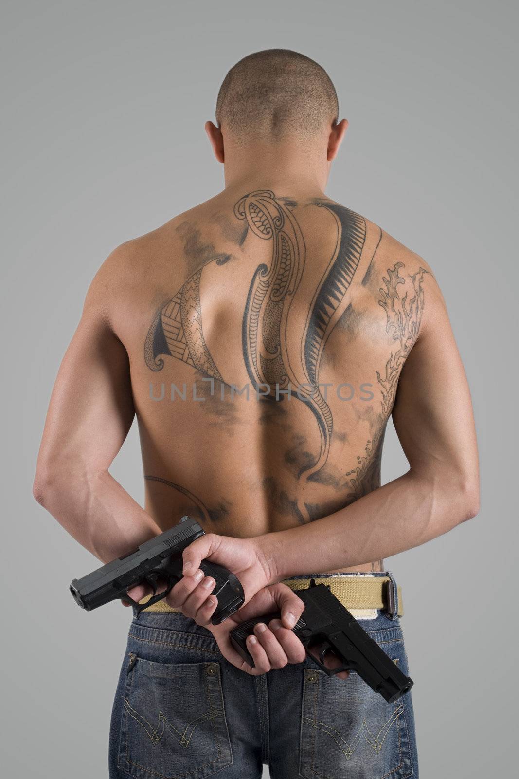 A young, muscular brazilian man in a studio shot on a gray background.