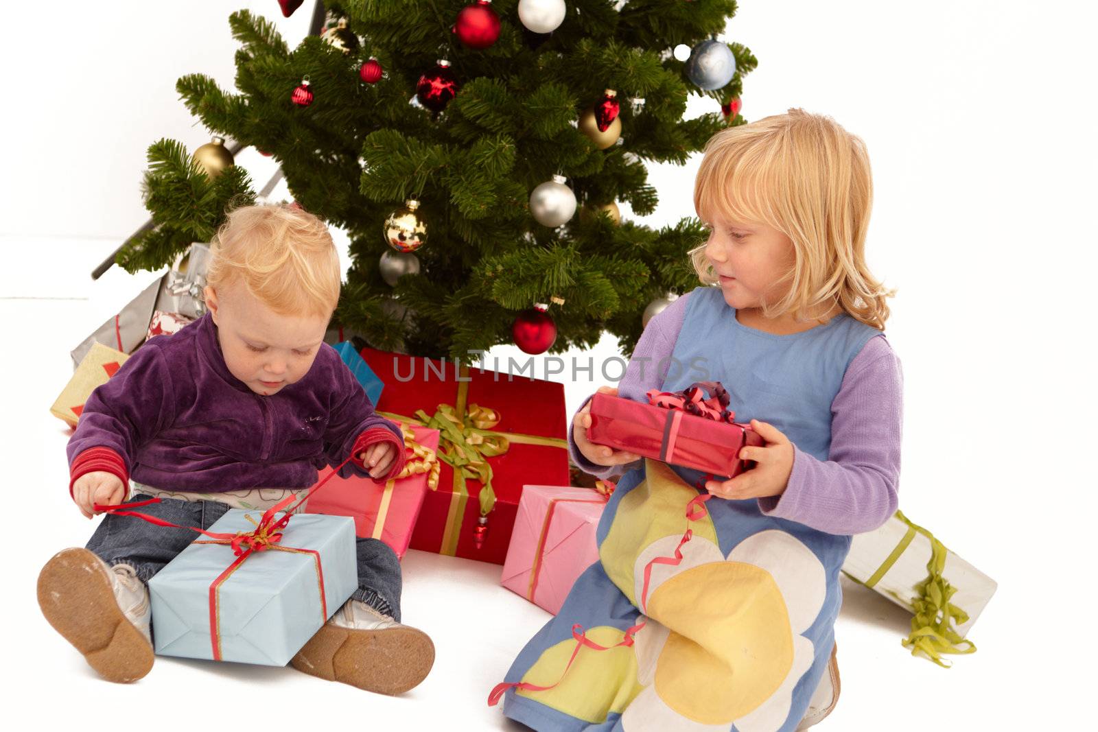 Christmas - Kids opening presents under tree by FreedomImage