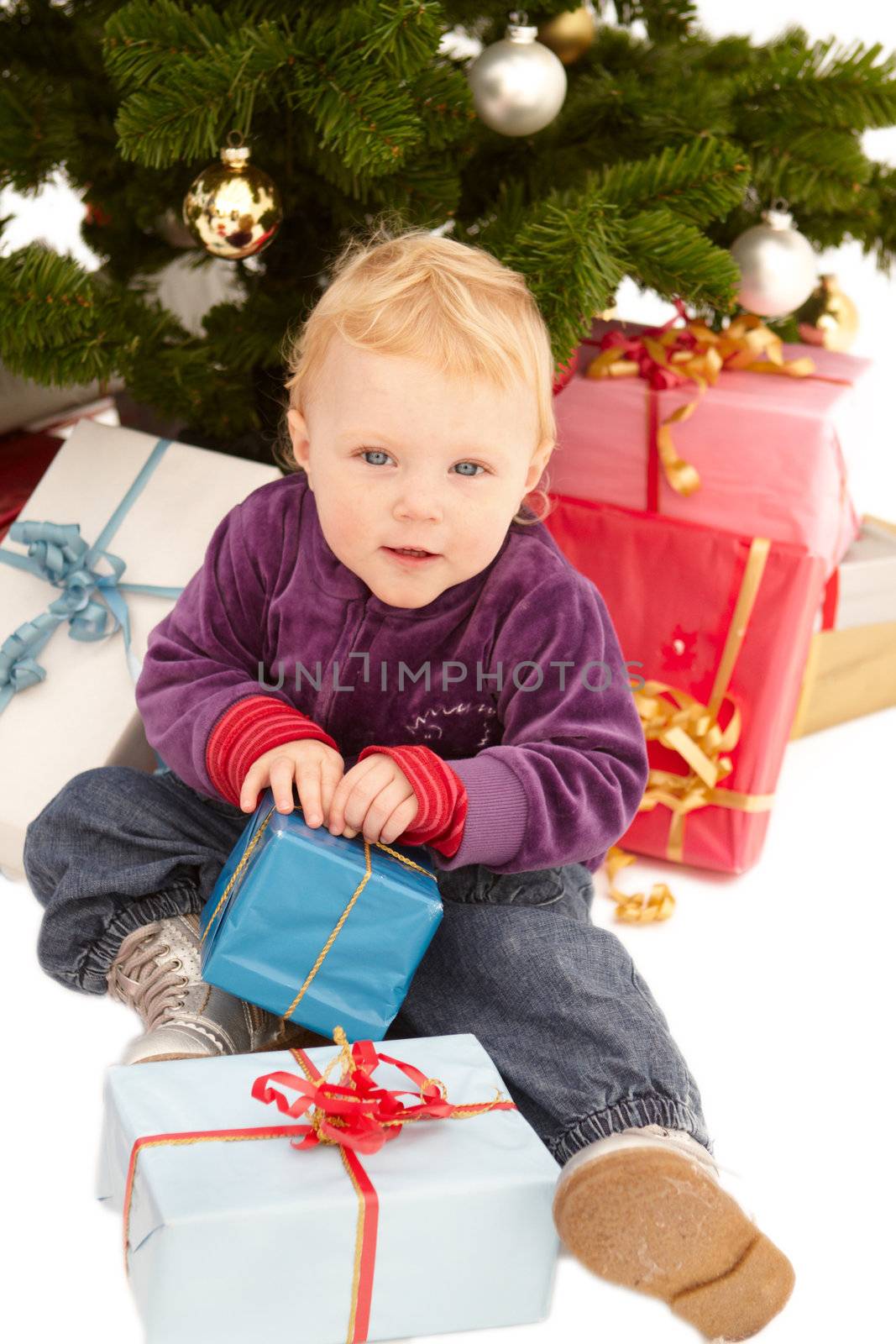 Cute little girl opening christmas gifts under a tree