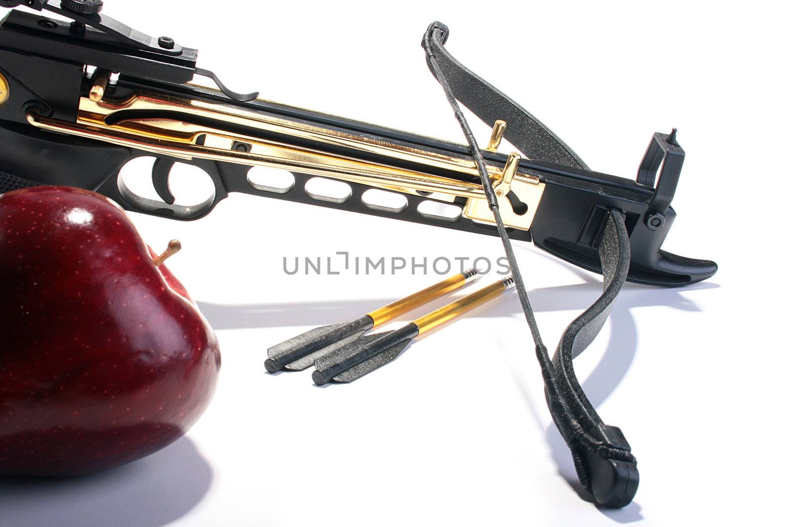 Crossbow with arrows and a red apple.