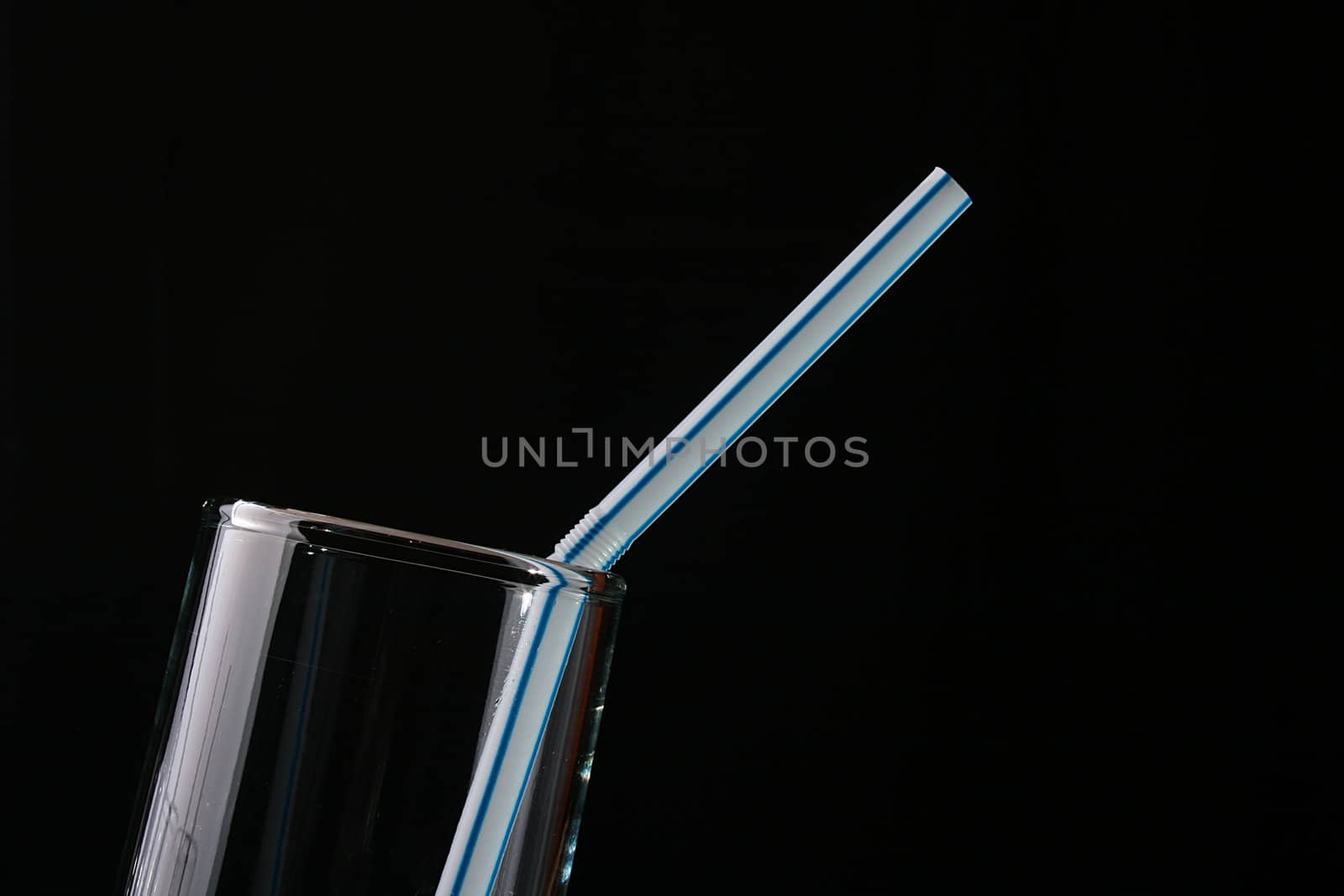 Empty glass glass with a tubule for a cocktail on a black background.