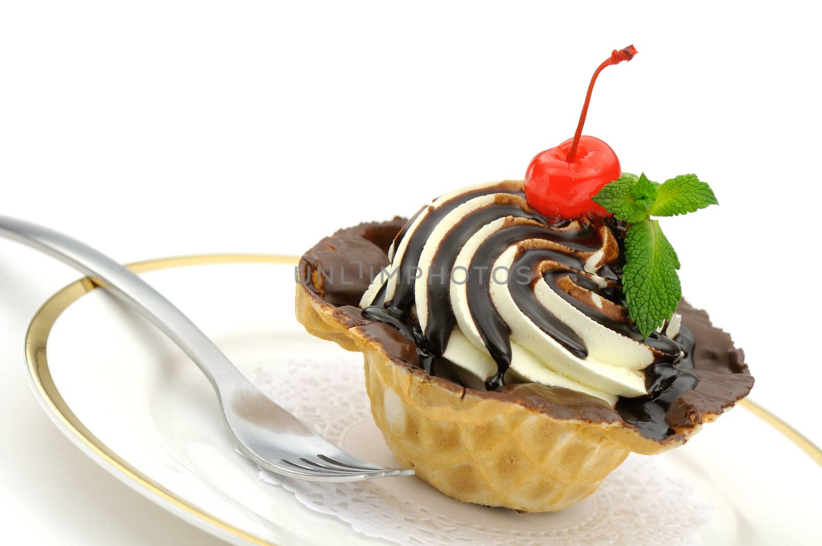 Delicious cream and chocolate cake in a wafer cup decorated with a candied cherry and mint leaves