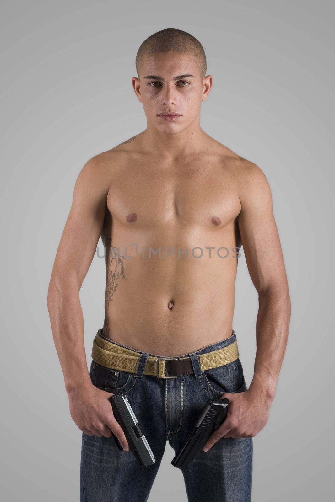 A young, muscular brazilian man in a studio shot on a gray background.