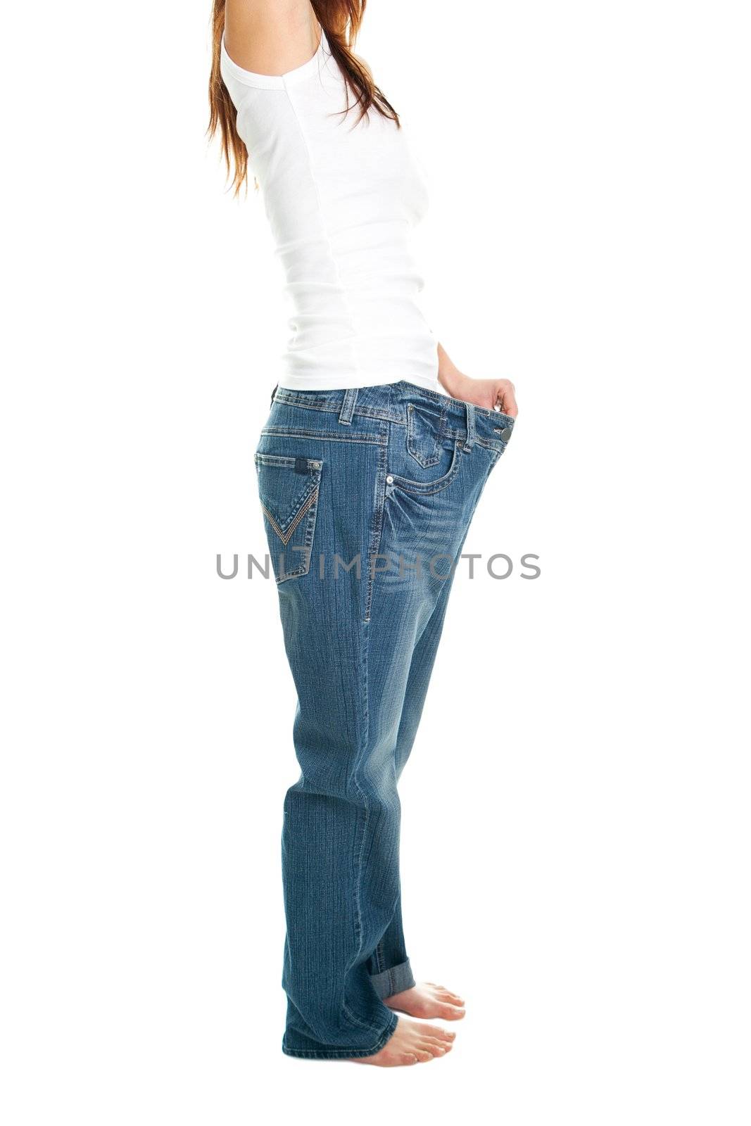 Slim woman pulling oversized jeans. Weight loss concept. Isolated on white
