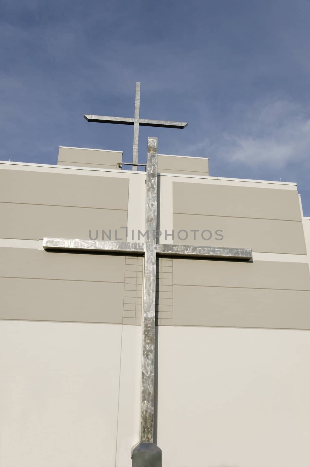 Two crosses on a church with a blue sky above it.