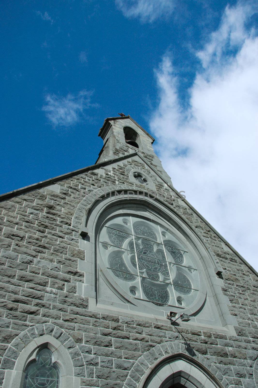 the front face of an irish church with a blue sky background