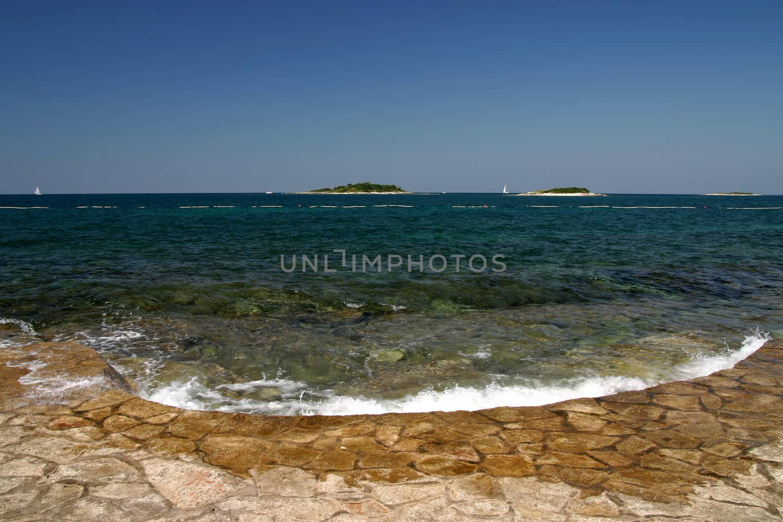 Wave bashing on sore with islands in the background