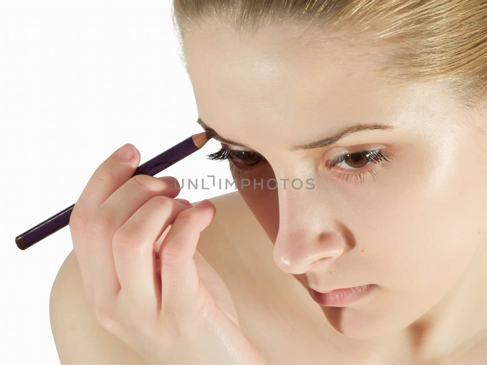 A young woman putting make up on her face