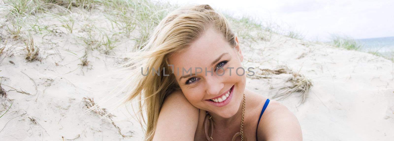 beautiful young blond girl sitting on the beach 