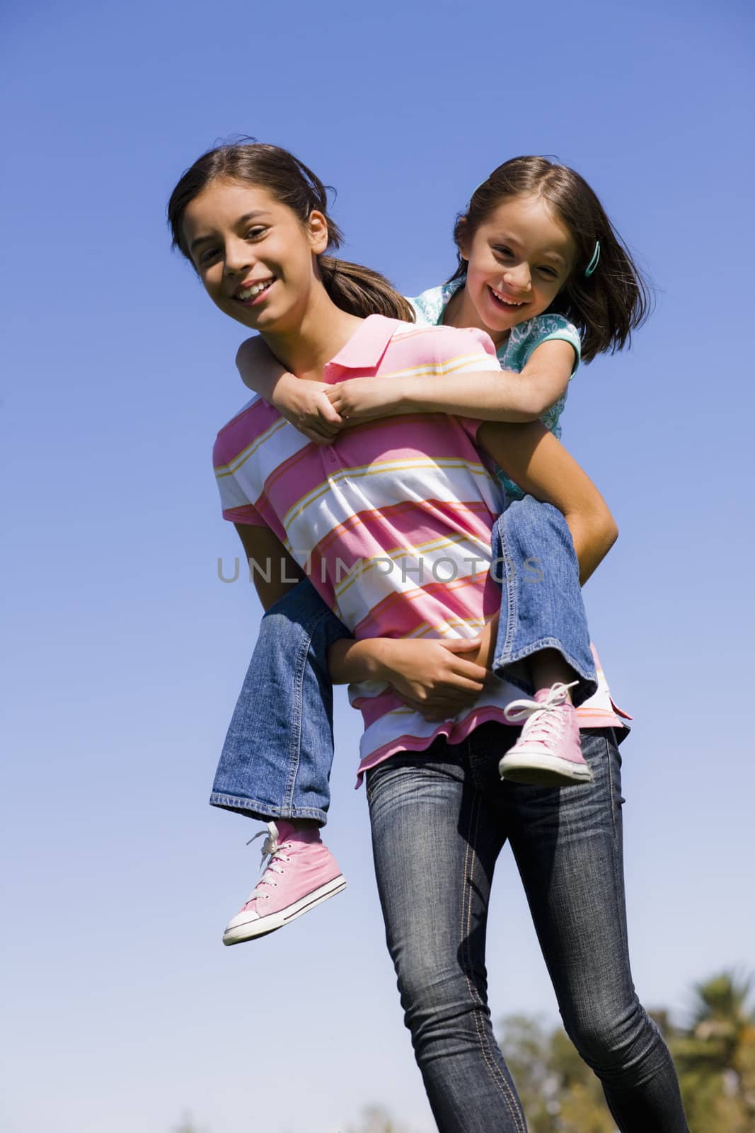 Teenage Girl Giving A Piggyback Ride To Younger Sister