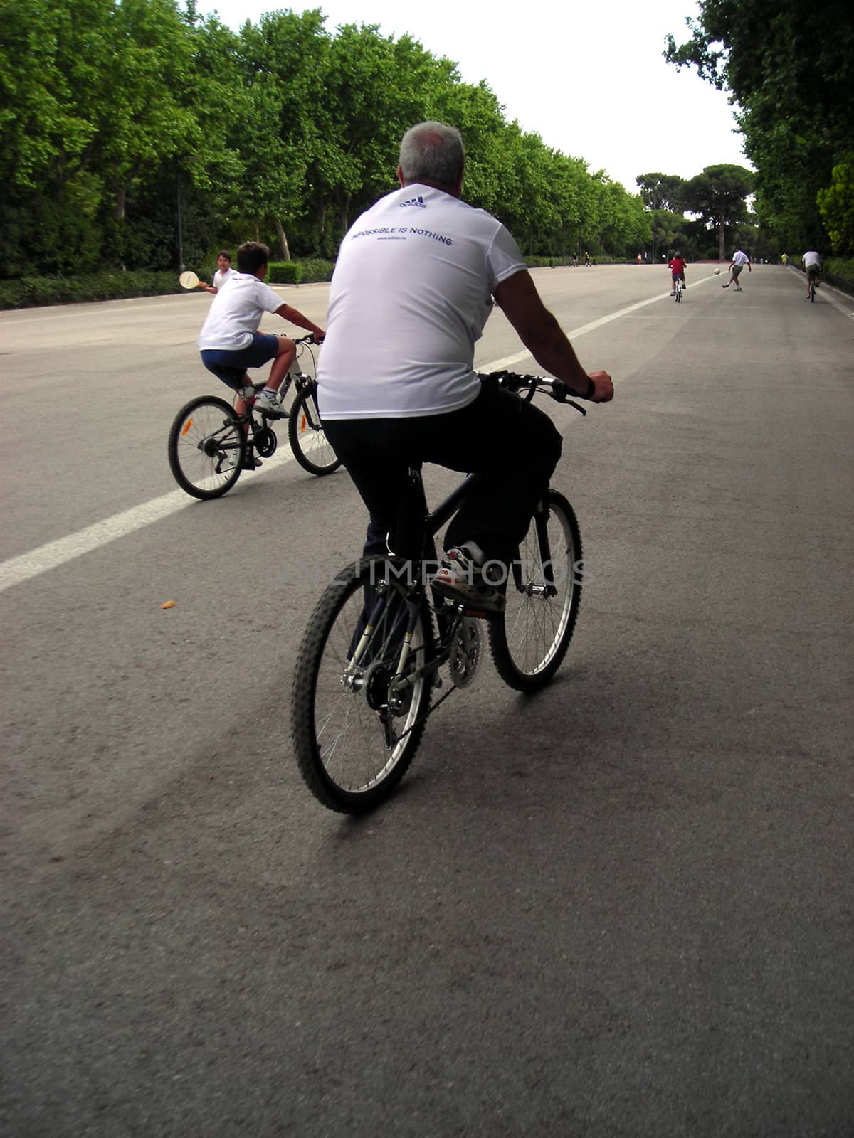 Two generations cycling quietly at Retiro Gardens in Madrid.