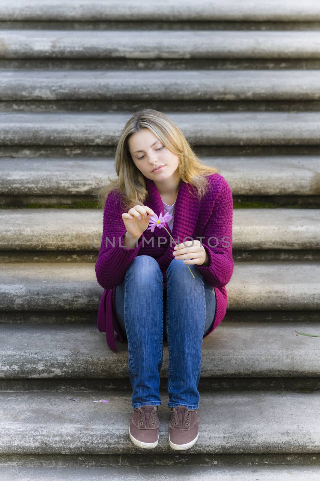 Pretty Blond Teen Girl Sitting on Stairs Holding a Daisy