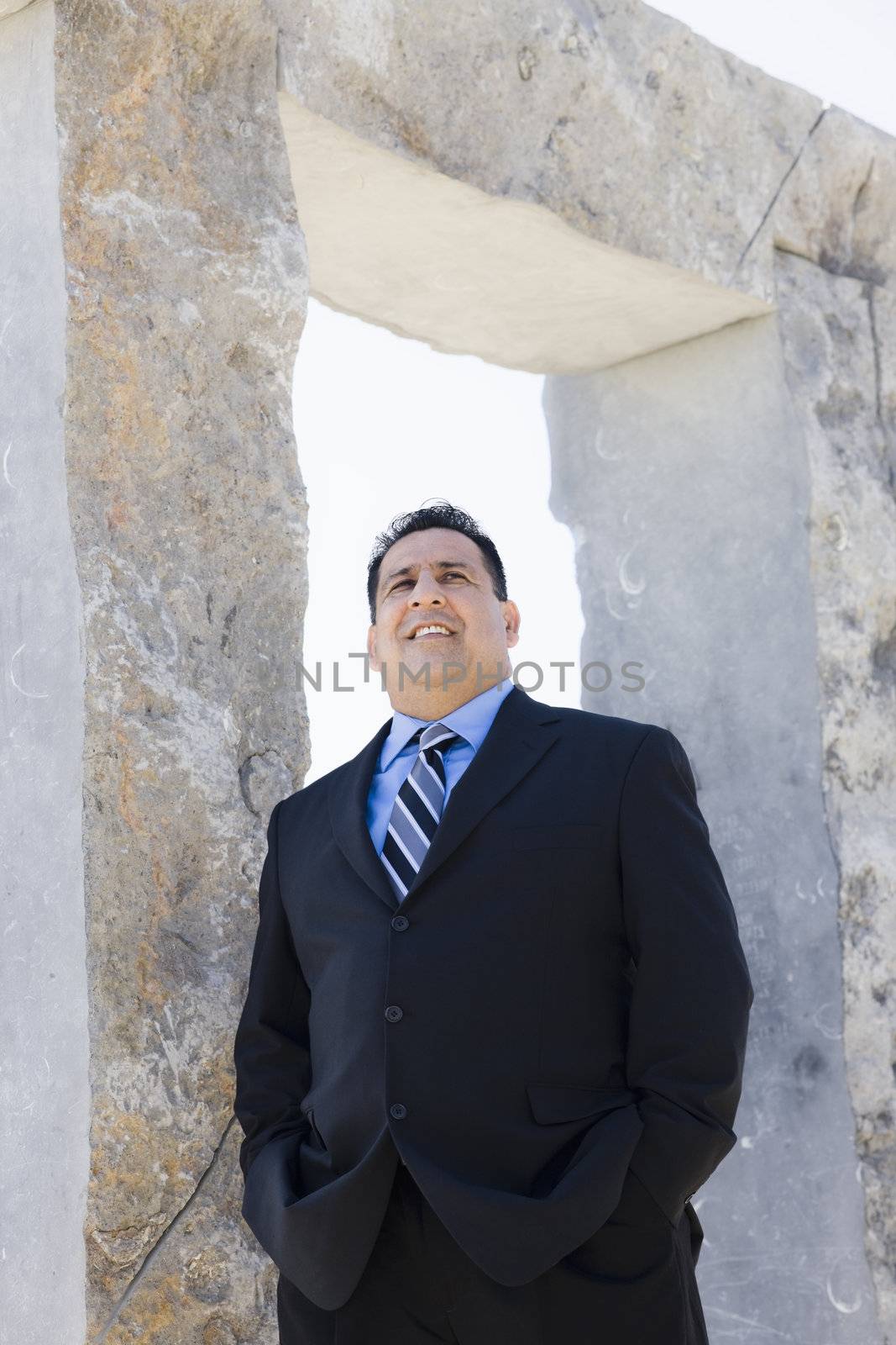Businessman Standing By An Archway Looking Away From Camera