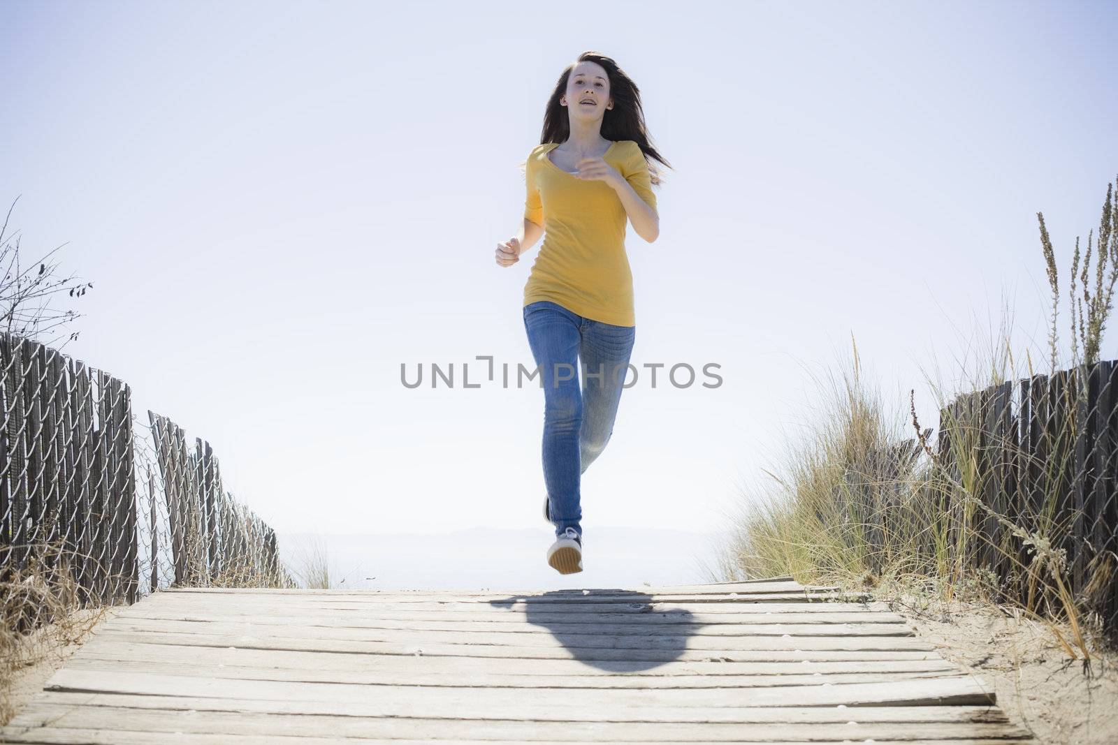Girl Running On Beach Walkway by ptimages