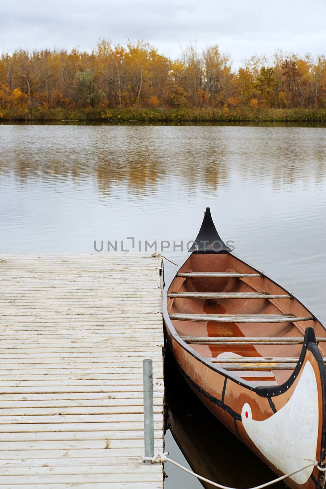 A canoe docked and floating on the river, shot on a cloudy day