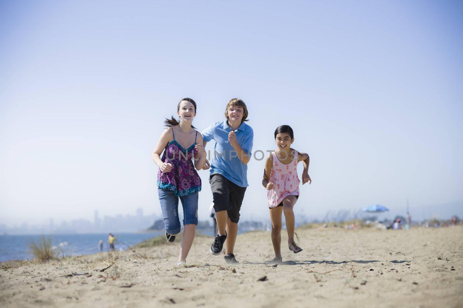 Three Kids Running on Beach by ptimages