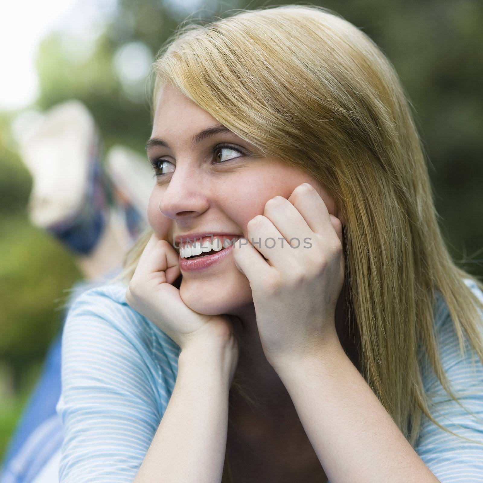 Smiling Teen Girl Resting head on Her Hands Looking Away From Camera