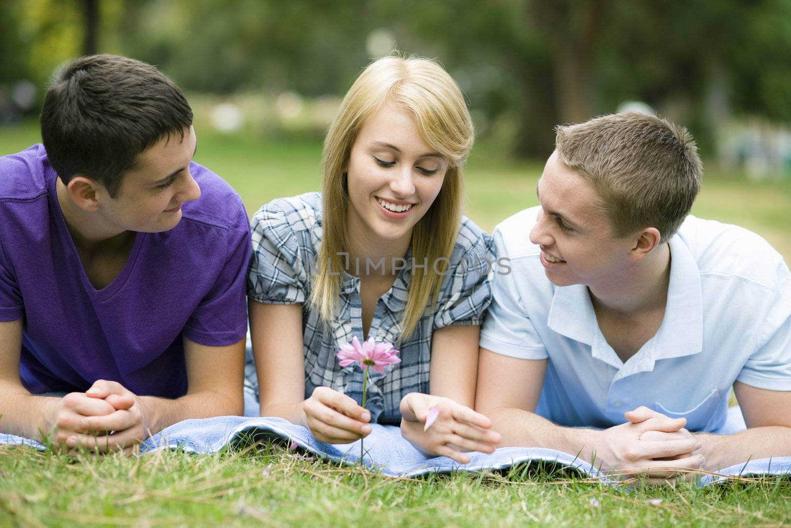 Group of Three Teens Lying on Blanket in a Park