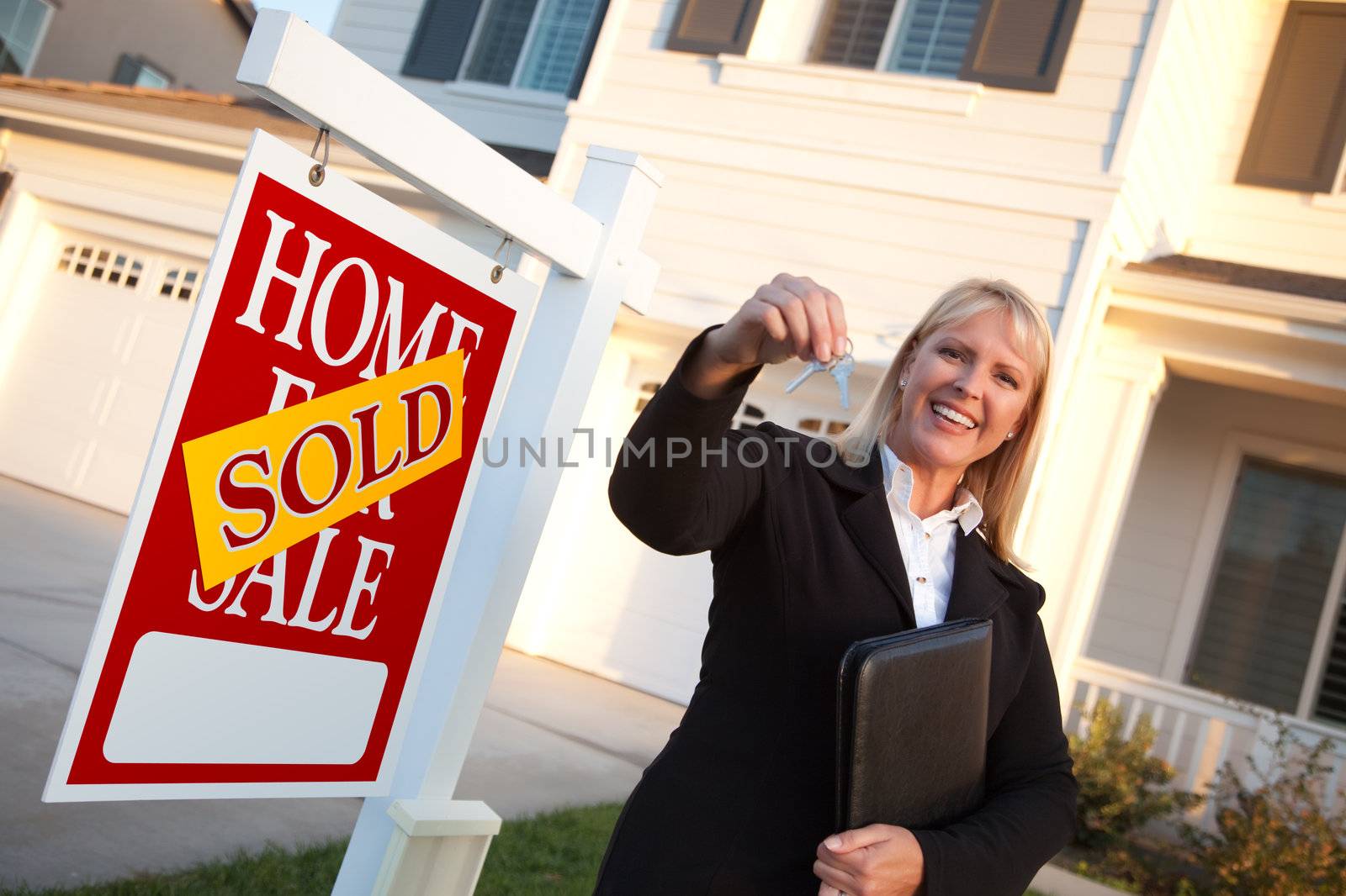 Female Real Estate Agent Handing Over the House Keys in Front of a Beautiful New Home and Real Estate Sign.