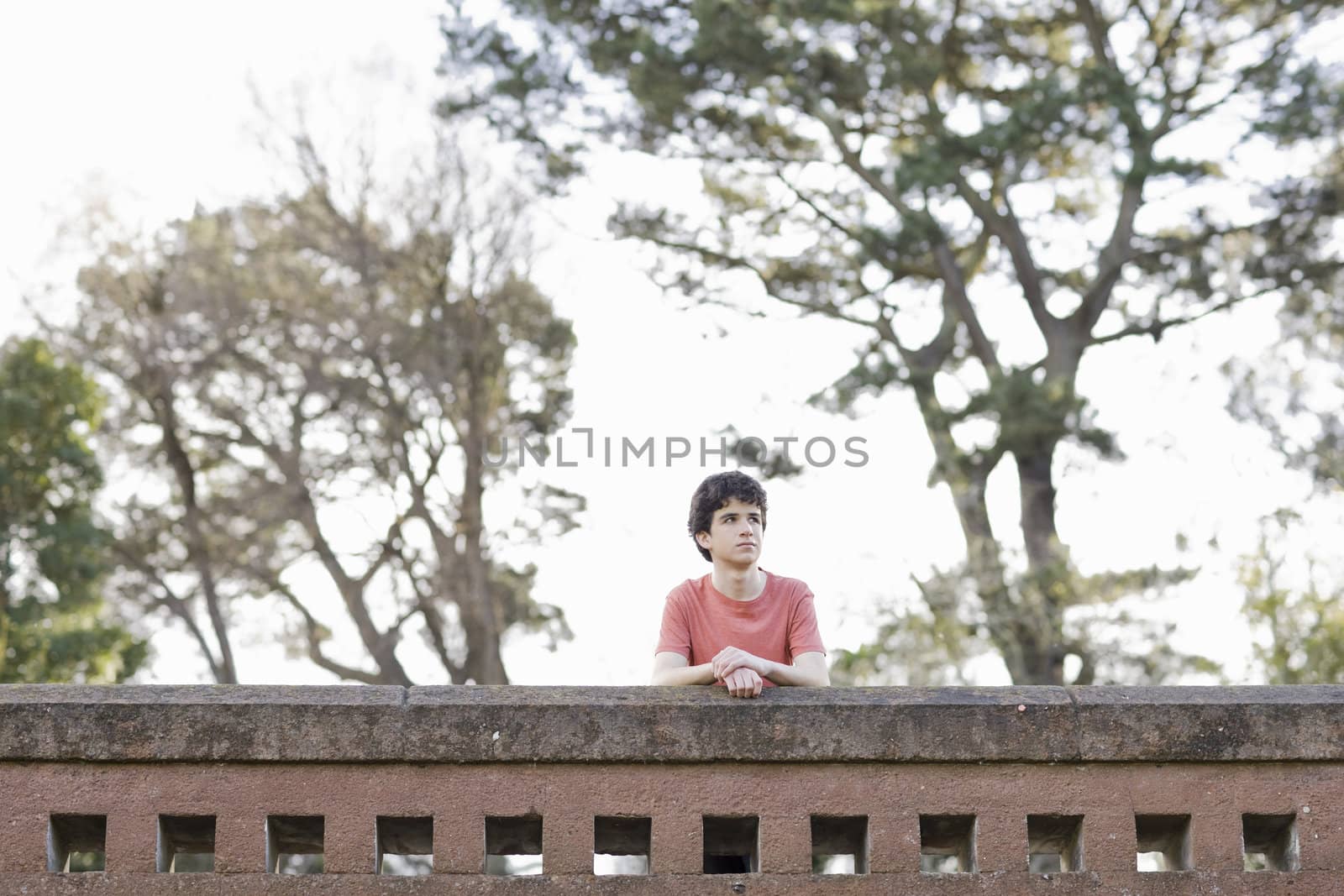 Teen Boy Outdoors Looking Away From Camera While Leaning on Wall