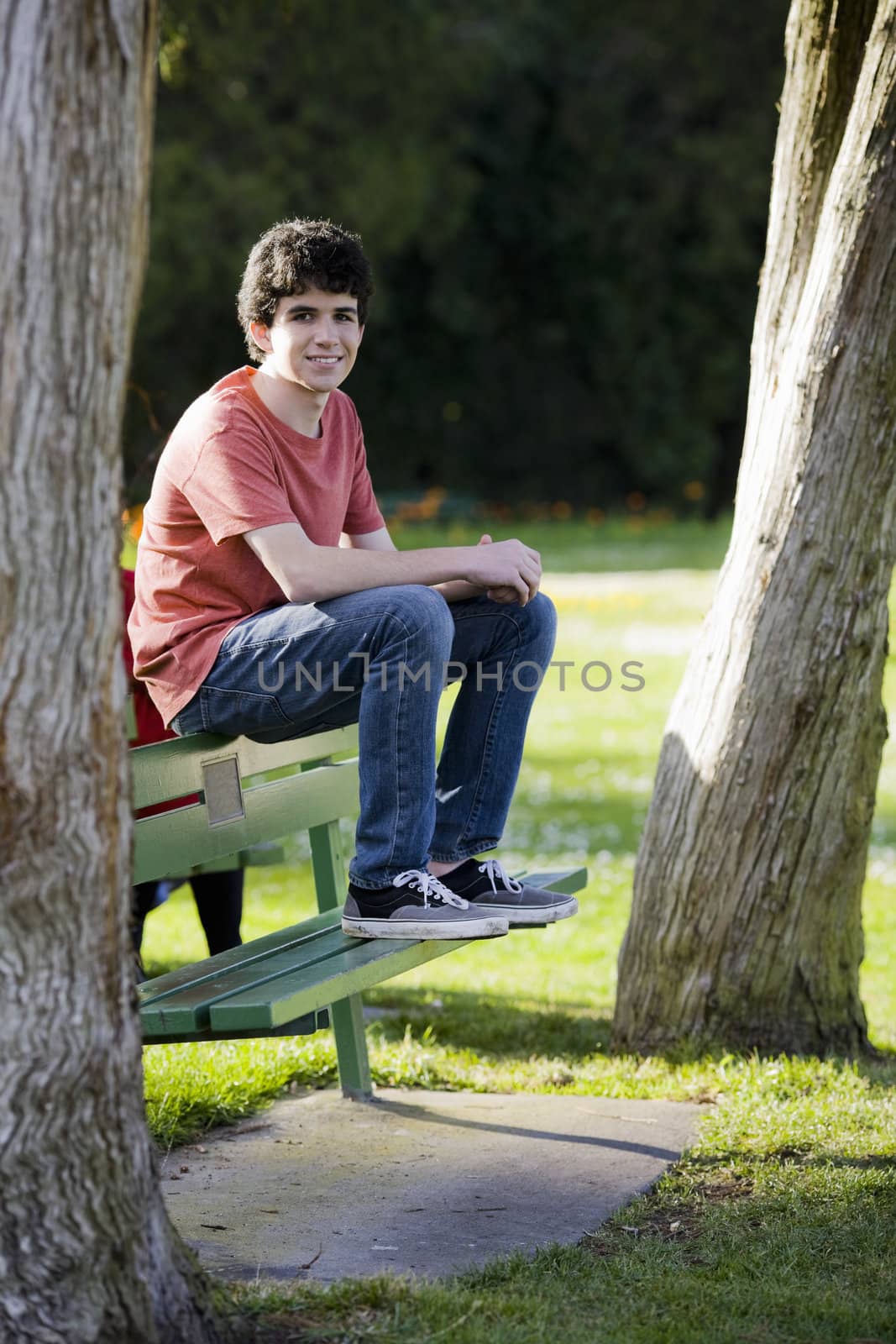 Smiling Teenage Boy Sitting on Bench in Park