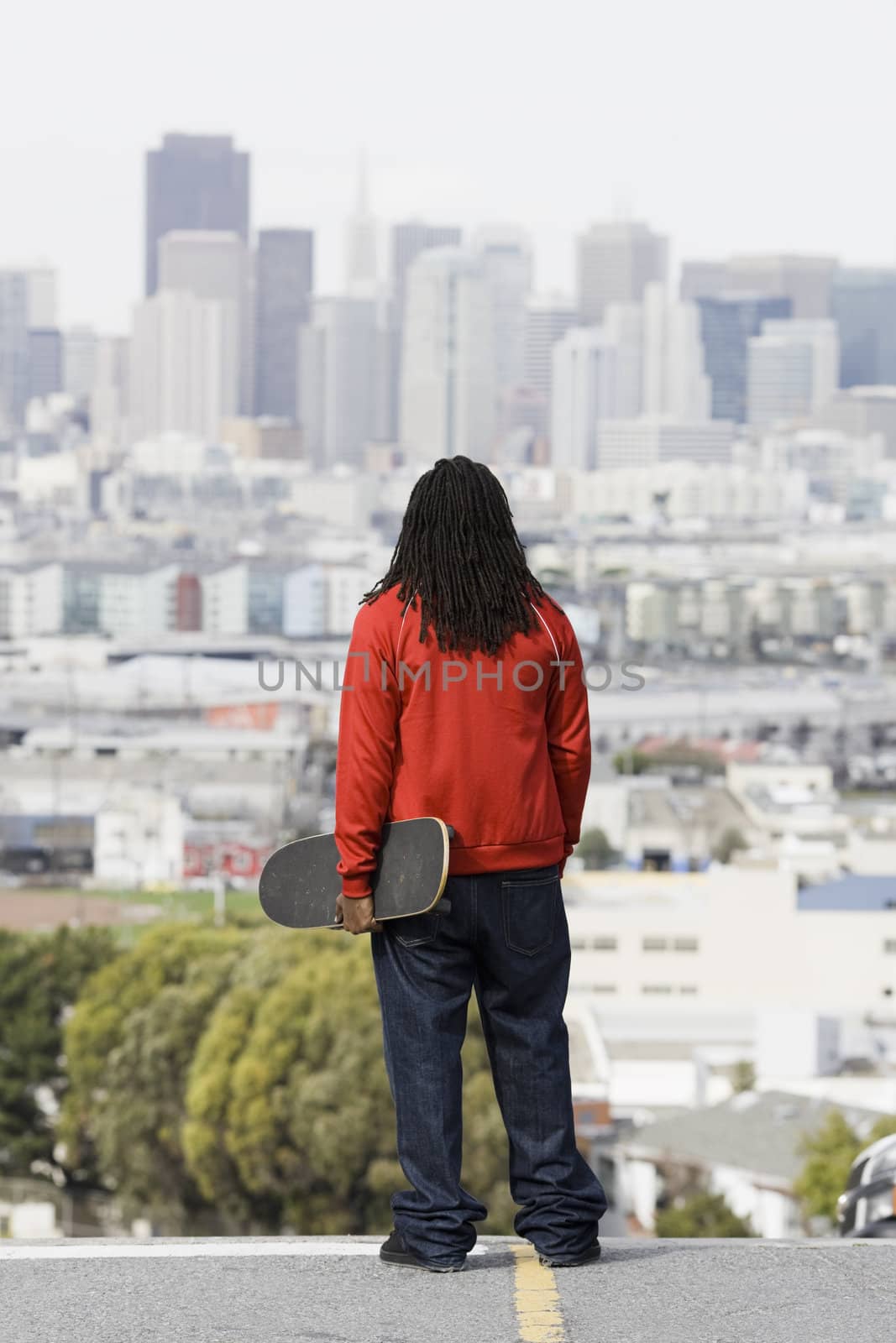 African American Boy Holding Skateboard Looking at City View