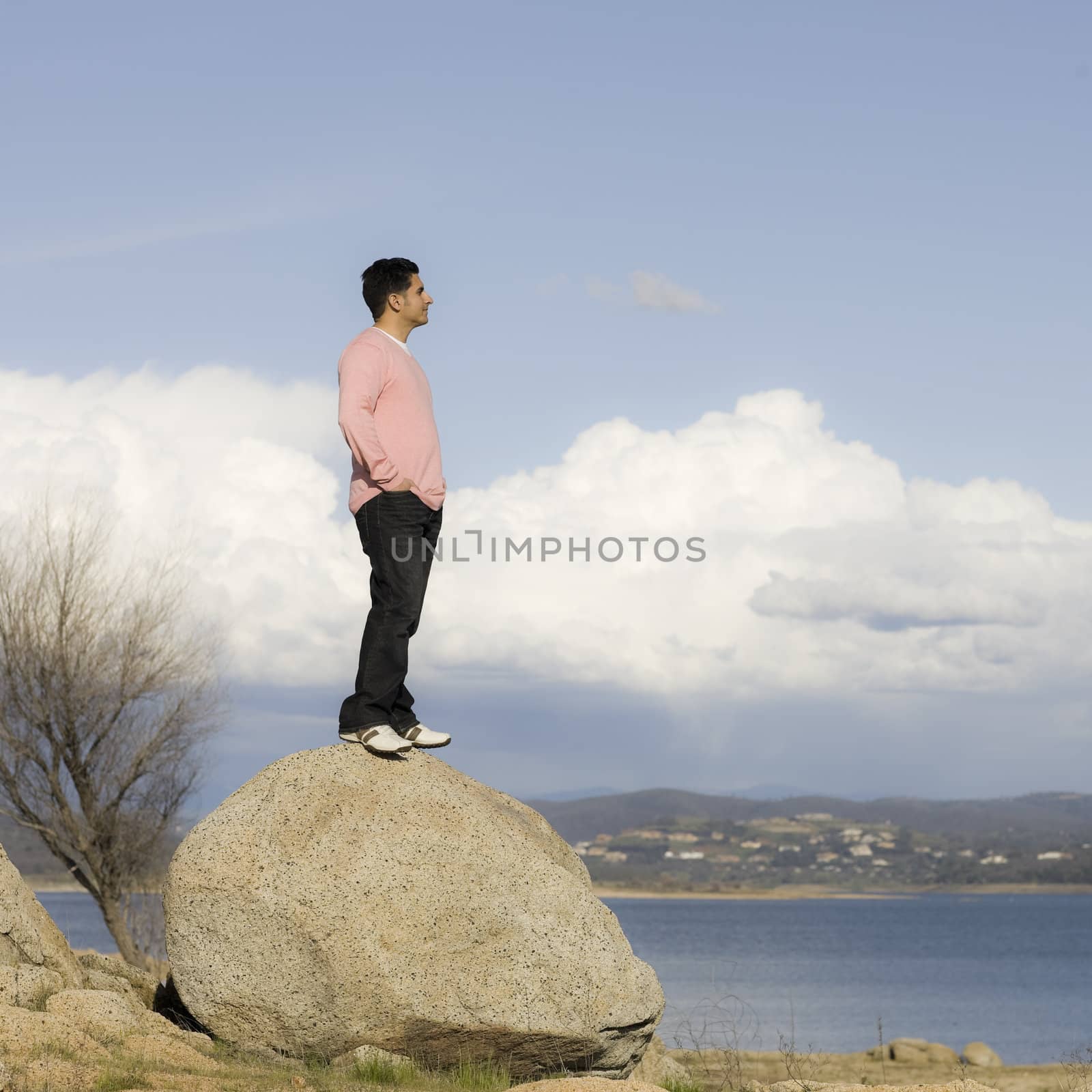Man Standing on Large Rock Overlooking Lake